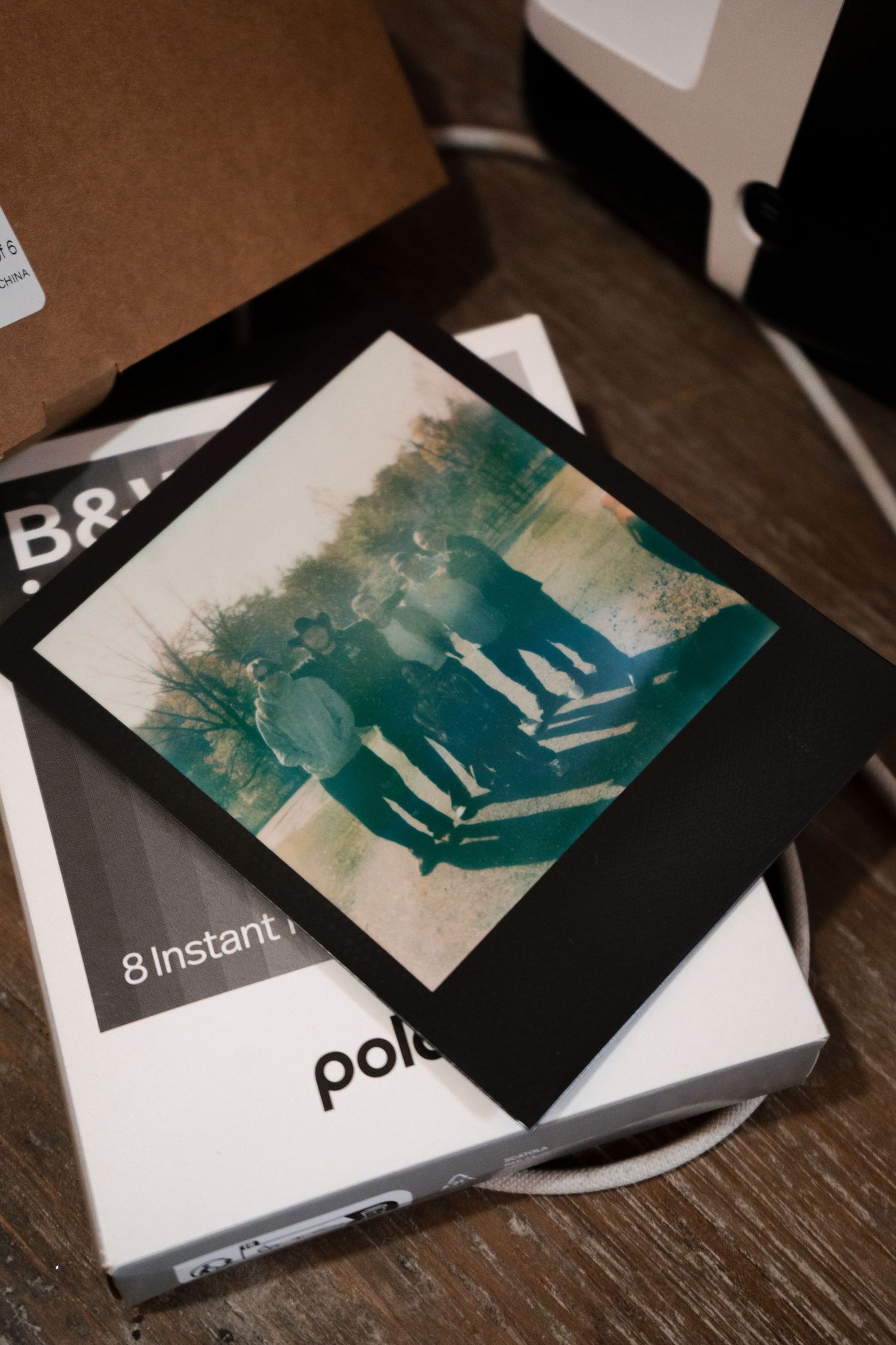 Polaroid instant film box and photographs displayed on a dark wooden surface with moody lighting.