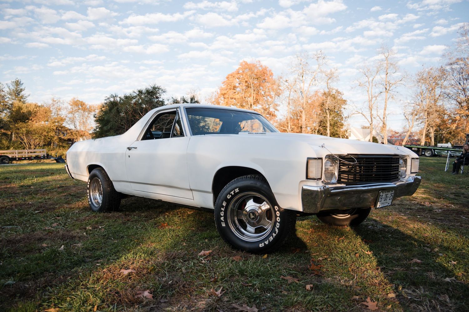 A white vintage Chevrolet El Camino photographed from multiple angles during sunset with autumn trees in the background.