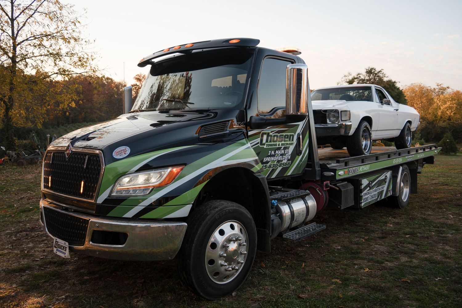 Custom wrapped commercial vehicle fleet with promotional graphics parked outdoors at sunset.