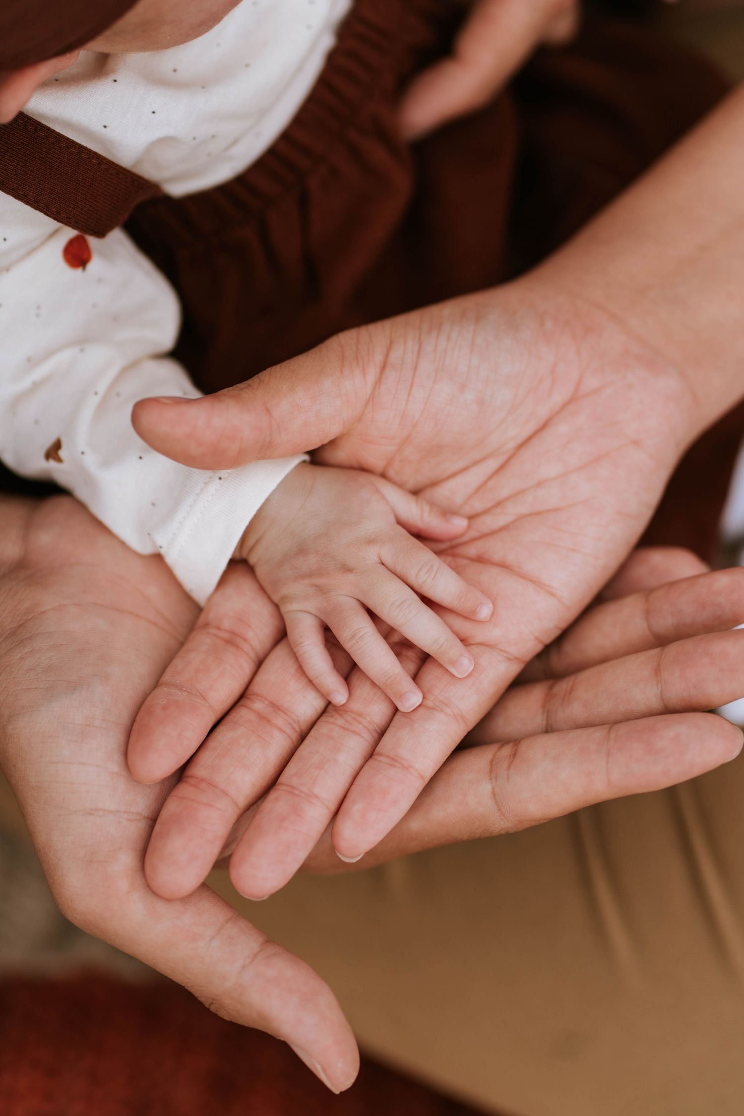 Close-up sequence of hands gently touching and intertwining in a tender moment against a warm background.