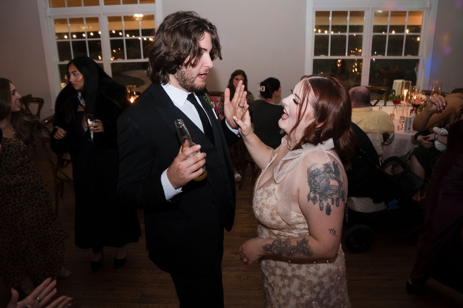 A couple shares a romantic dance moment at a wedding reception in an elegant venue with guests in the background.