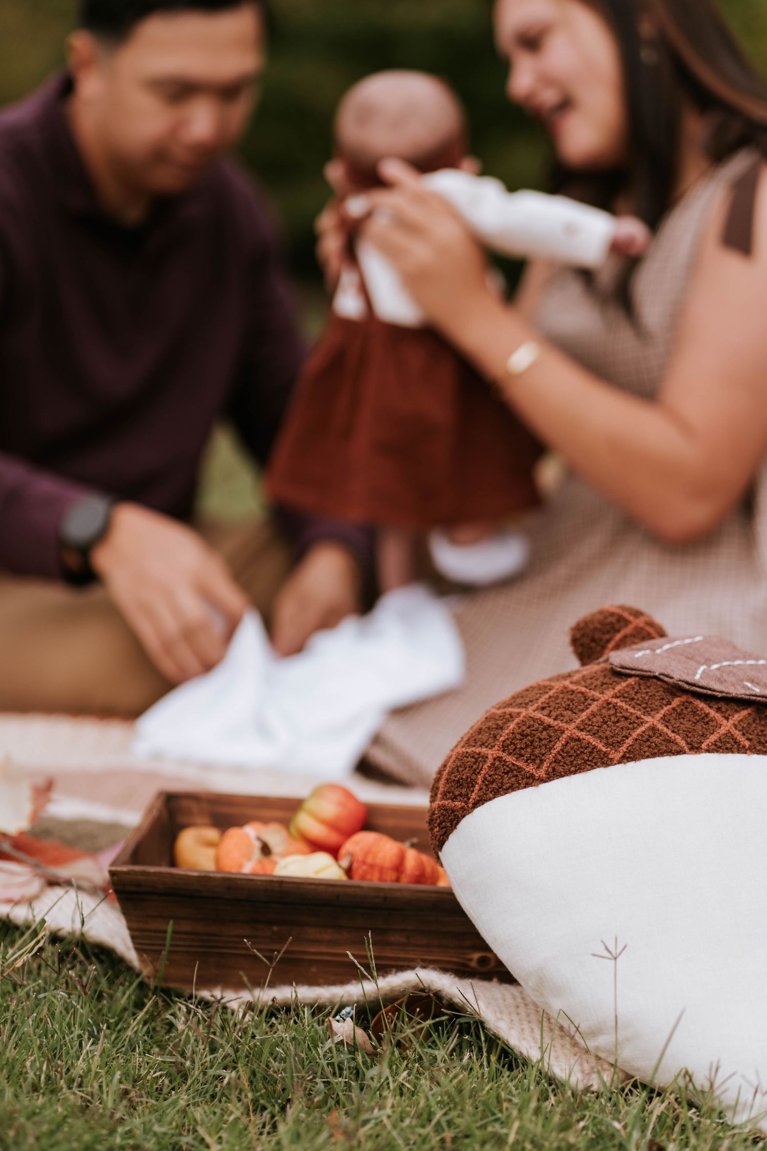 People gather outdoors for a picnic with wooden serving boards and fresh food on a grassy lawn.