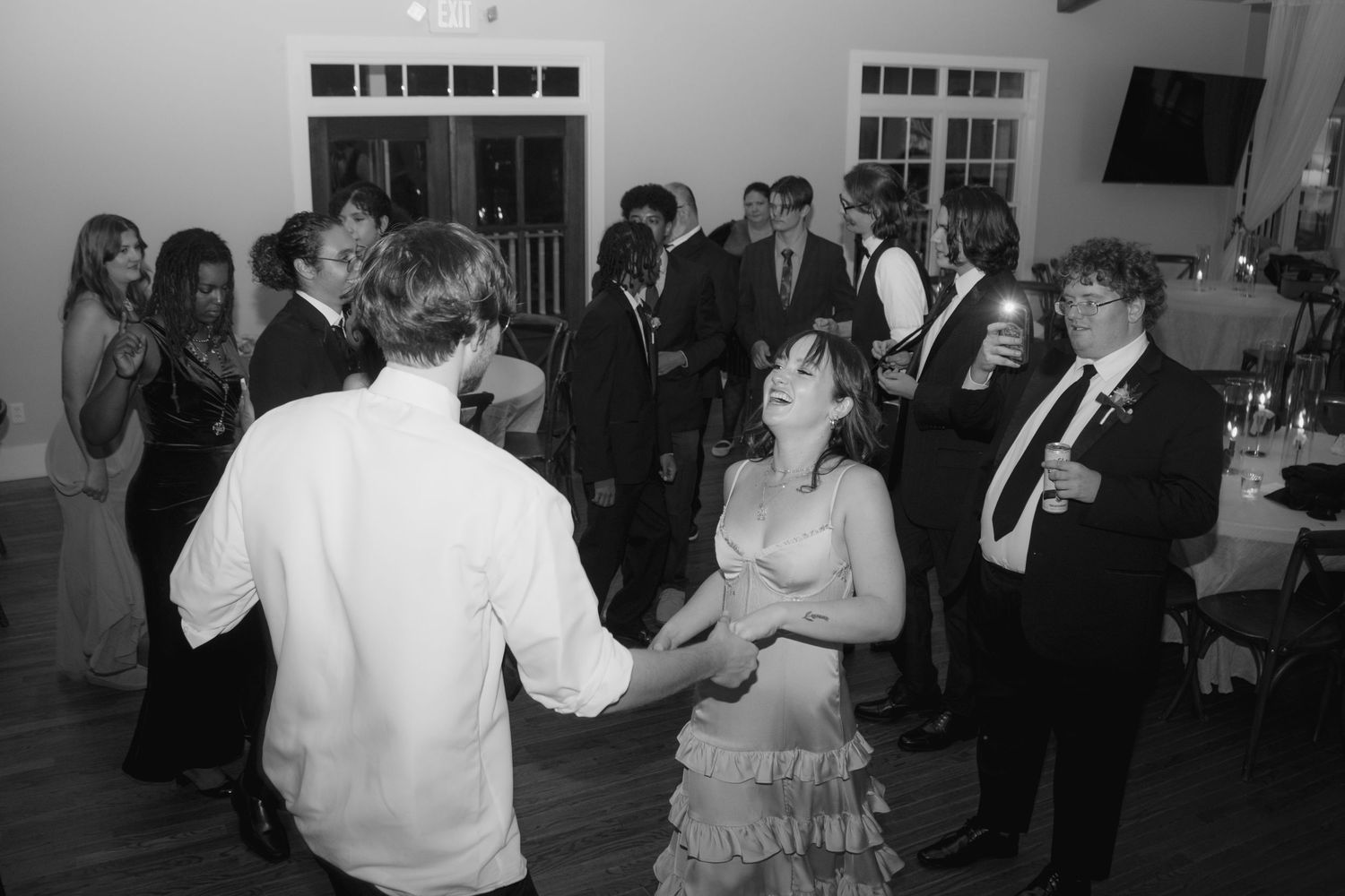 Wedding reception guests dancing in a dimly lit indoor venue.