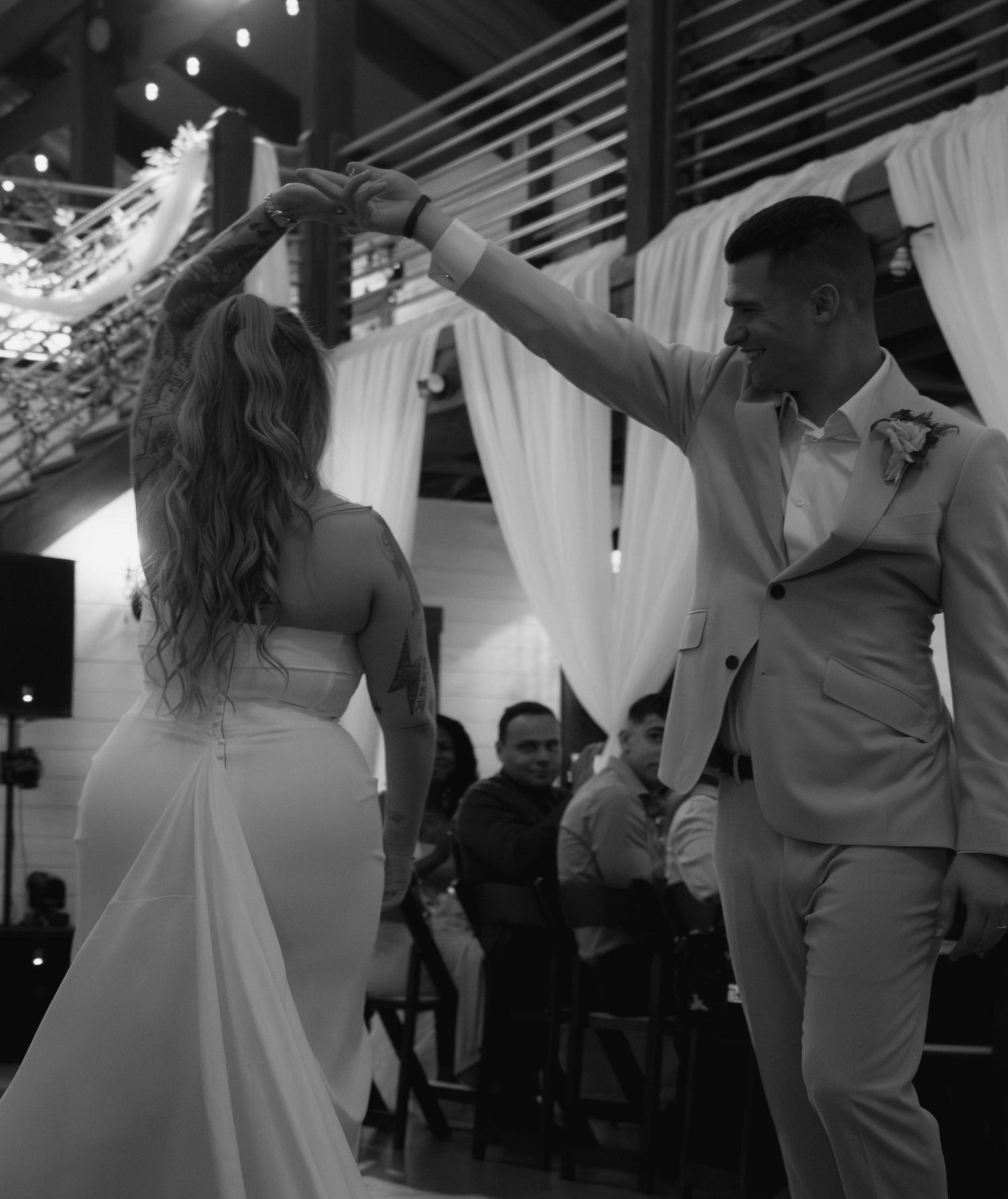 Black and white photo of bride and groom sharing first dance at elegant wedding reception venue.