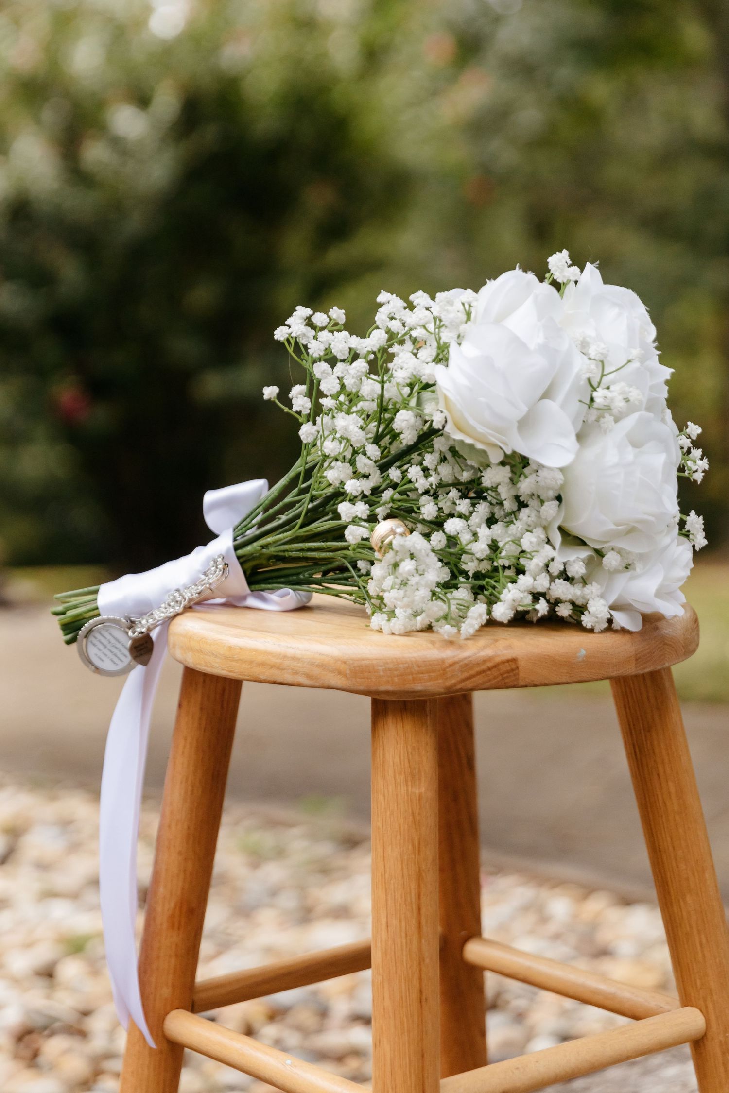 White floral arrangements with baby's breath and ribbons displayed on wooden stools create an elegant wedding ceremony decor.