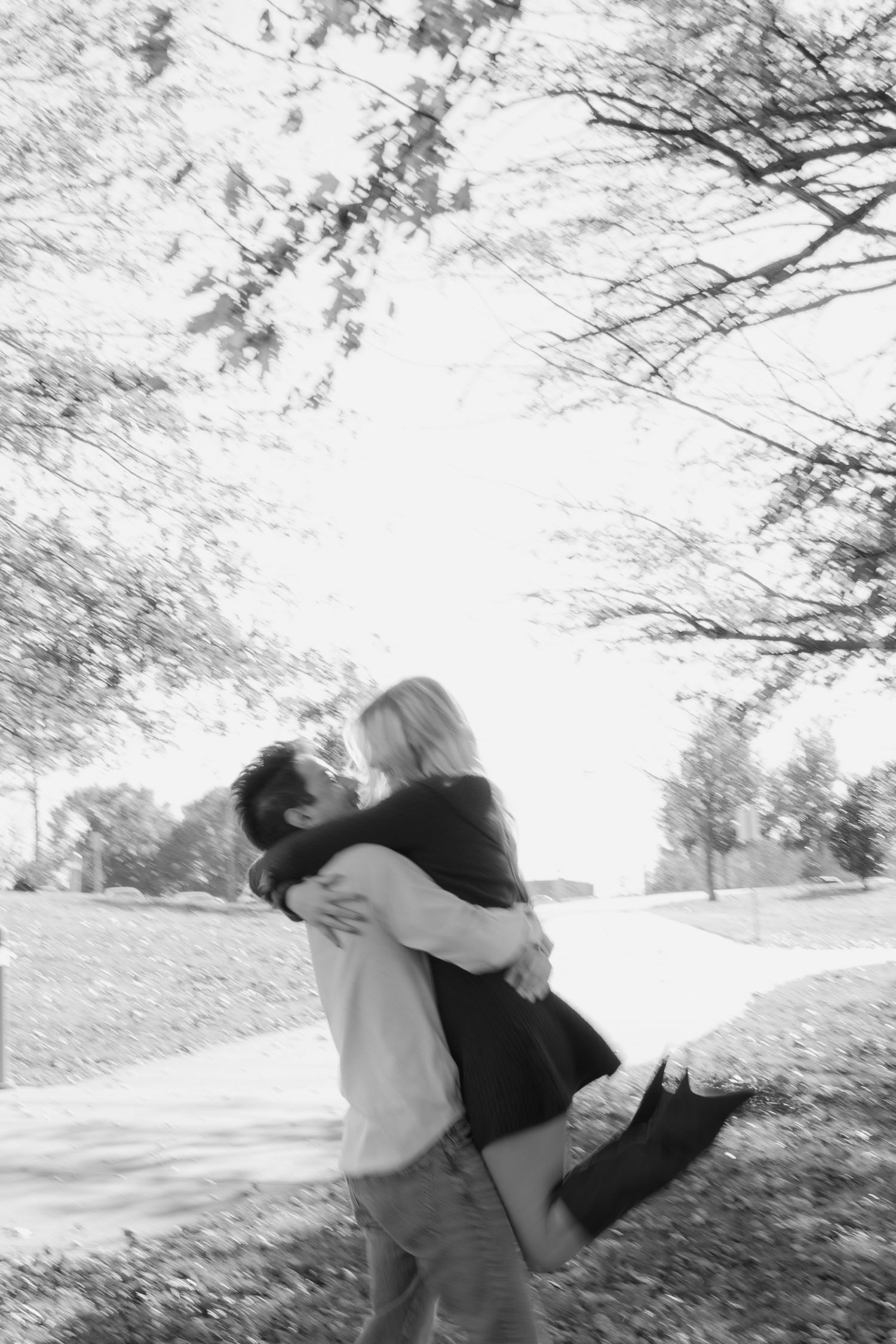 Two people share a tender embrace on a snowy winter day beneath snow-covered tree branches.