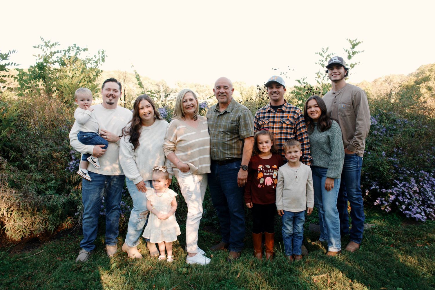 A collection of outdoor family portrait photos taken at sunset in a garden setting with natural greenery and flowers.