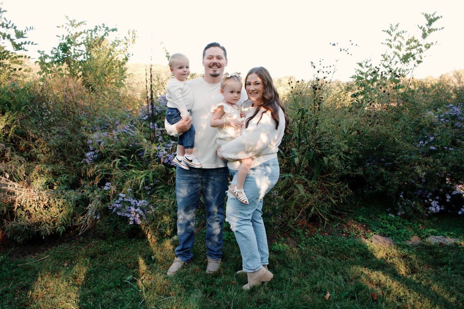 A family enjoying a playful moment together in a sunlit garden during golden hour.