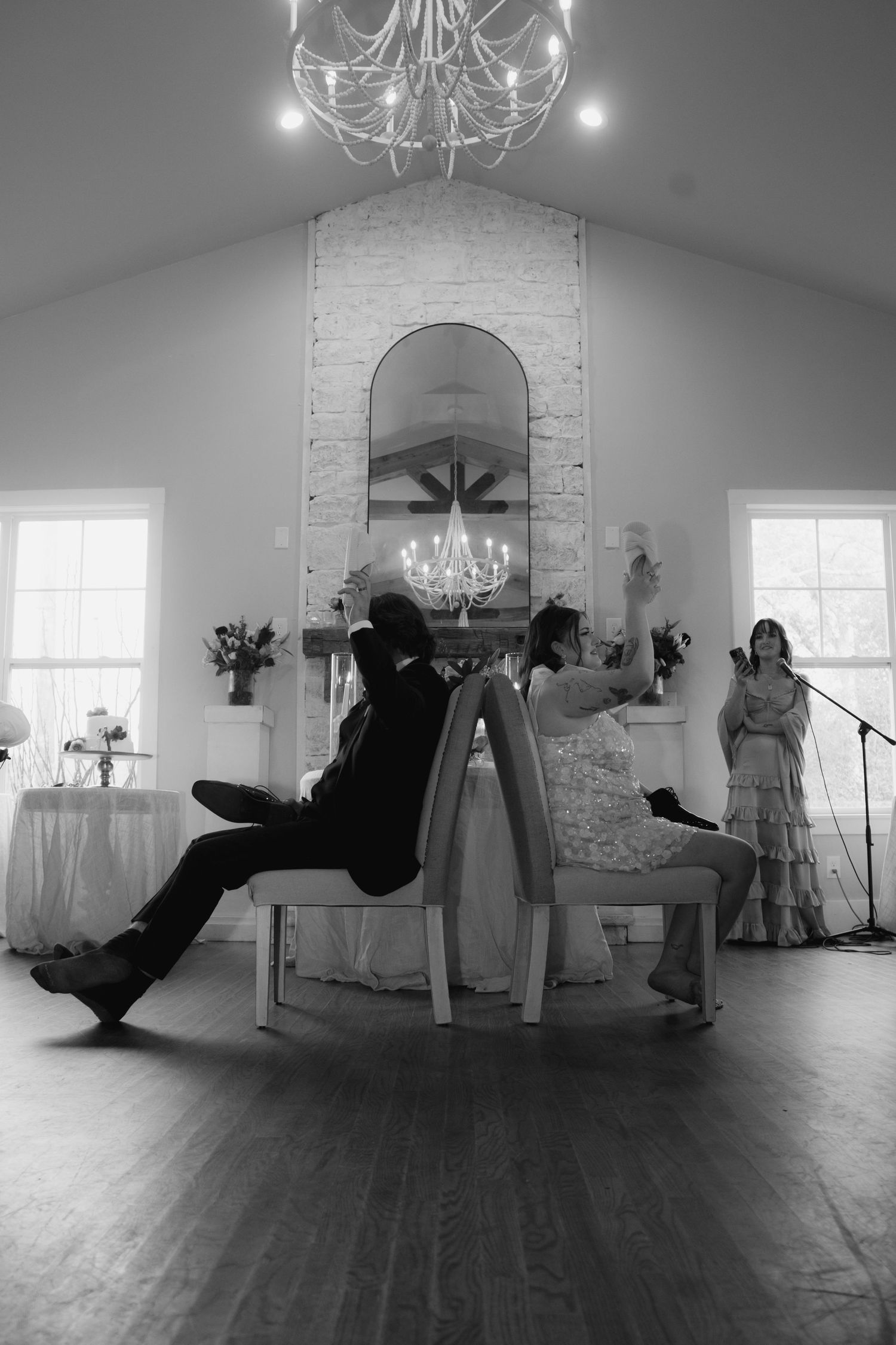Black and white panoramic sequence showing a dance performance in an elegant white room with hardwood floors and chandeliers.