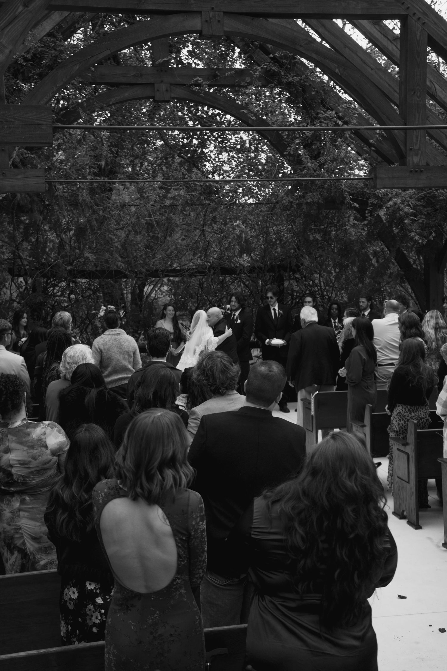 Wedding guests seated in rows under a dark outdoor pavilion during a ceremony.