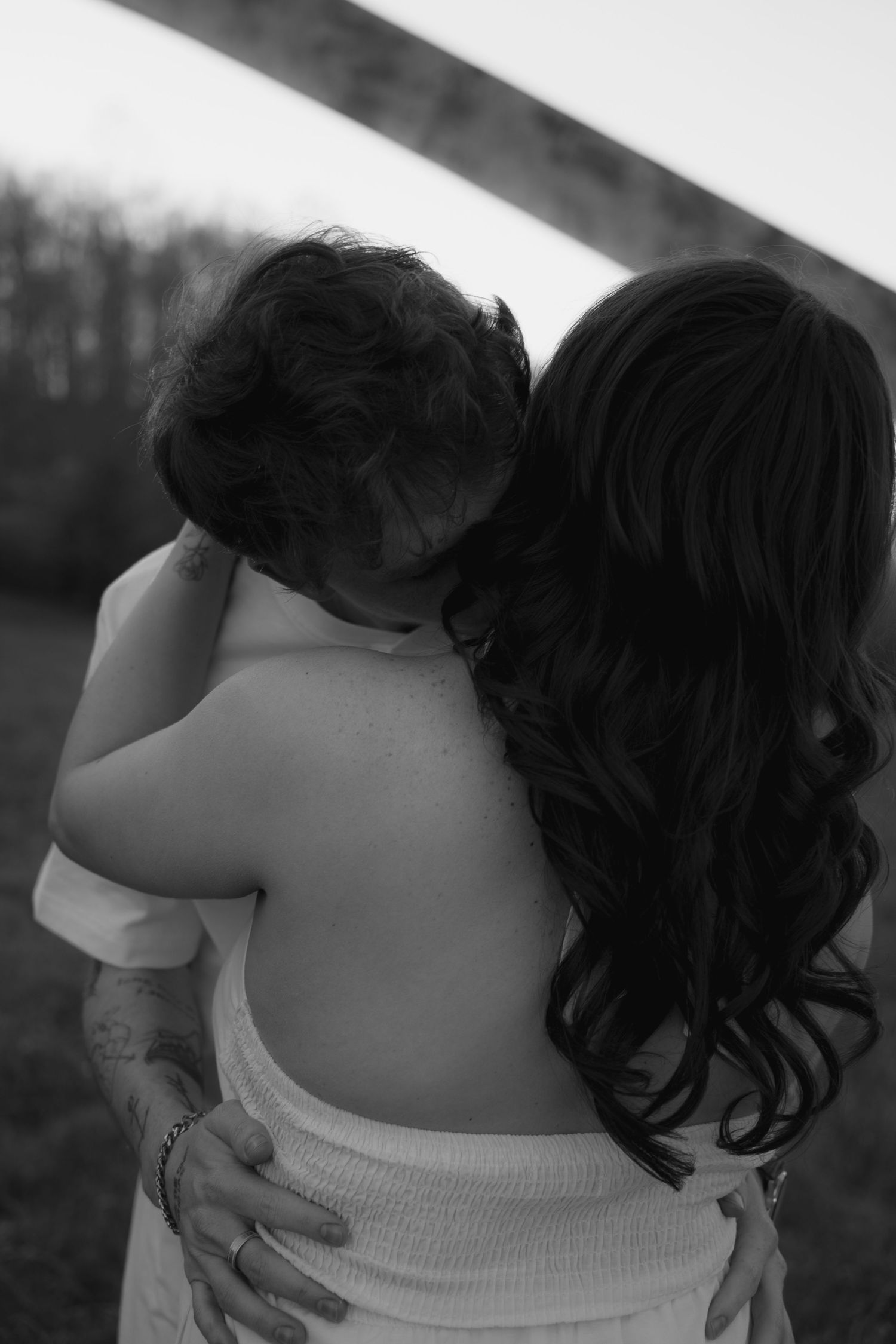 Black and white photo of a mother with long dark hair holding and embracing her young child outdoors.