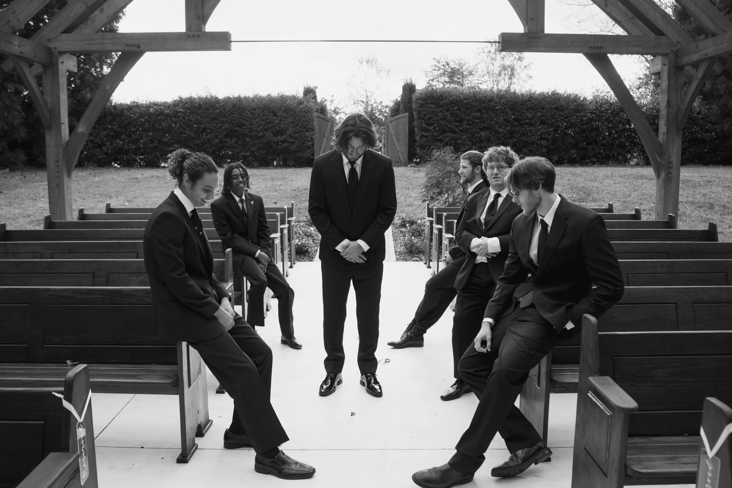 Black and white photo of groomsmen jumping in unison during outdoor wedding photoshoot.