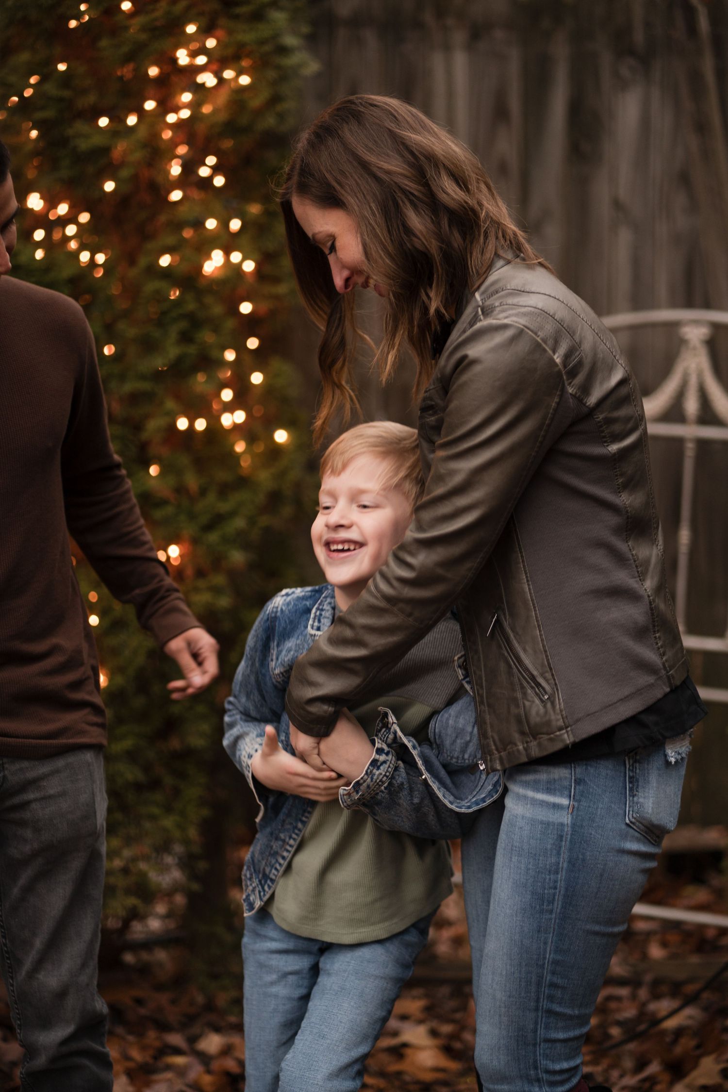 A series of candid photos showing playful hugs and laughter between family members against a backdrop of holiday lights.