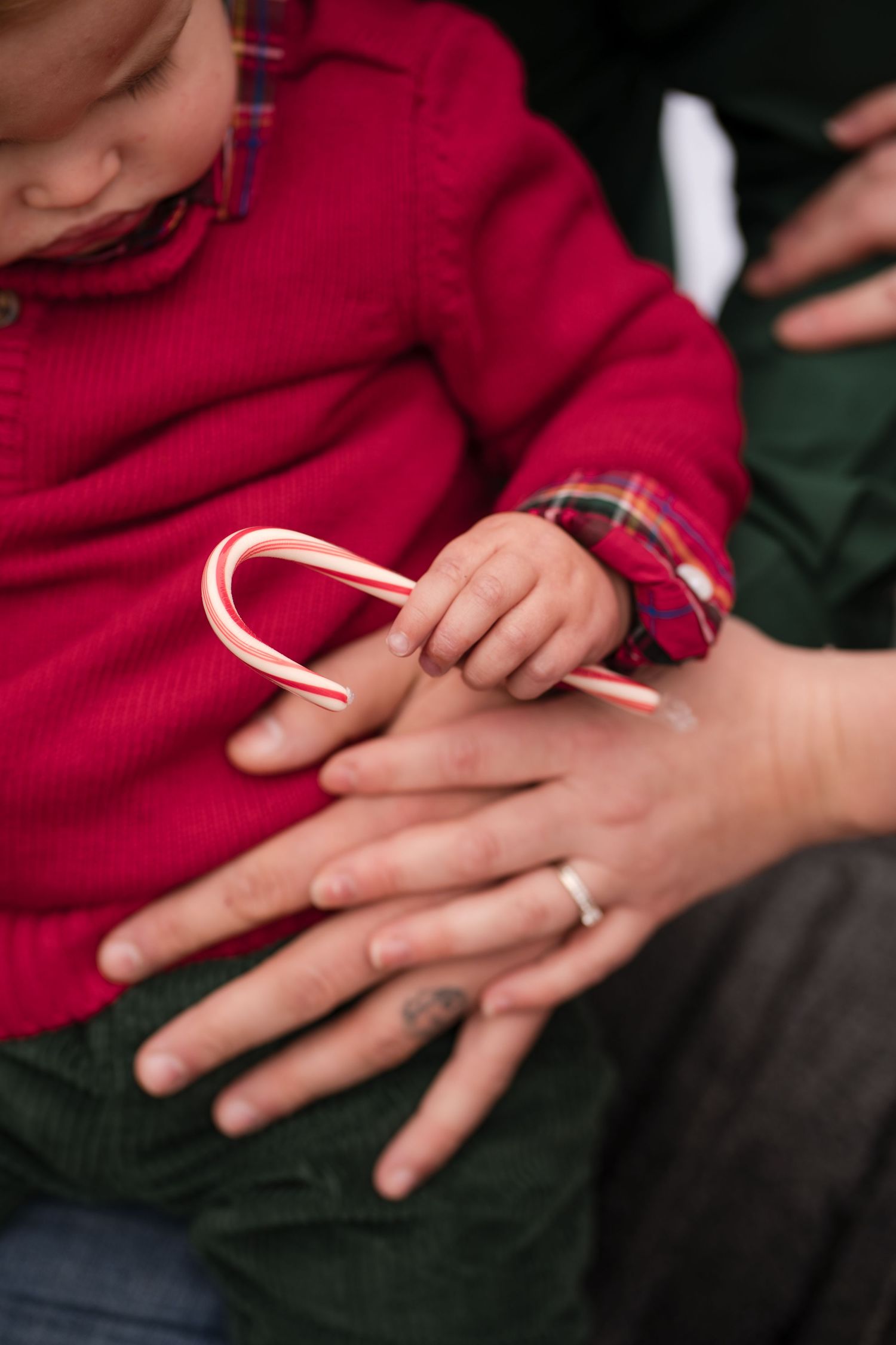 A sequence of hands holding and breaking apart a candy cane into smaller pieces against a dark background.