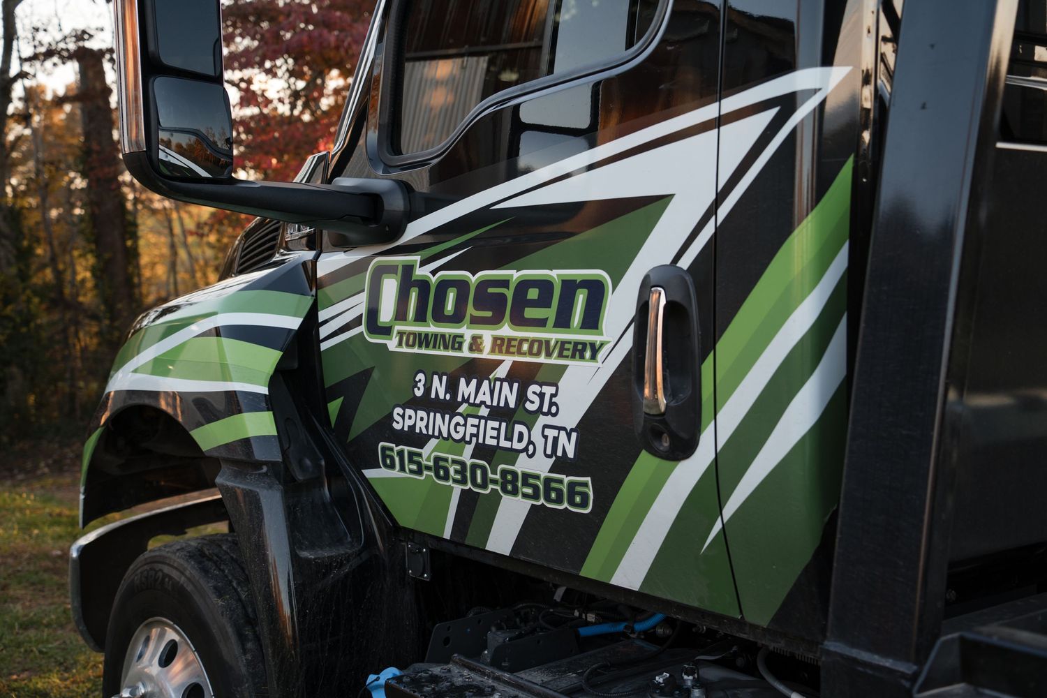 A green and black branded service vehicle parked outdoors with company graphics visible on its side panels.