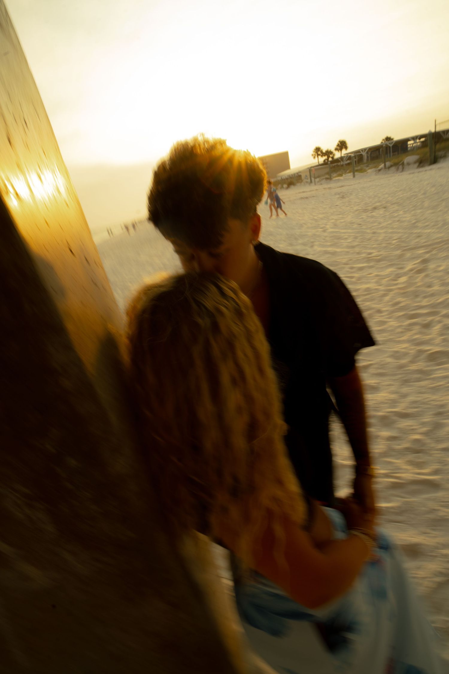 Couple walking on a sunny beach at golden hour, captured with artistic motion blur effect.