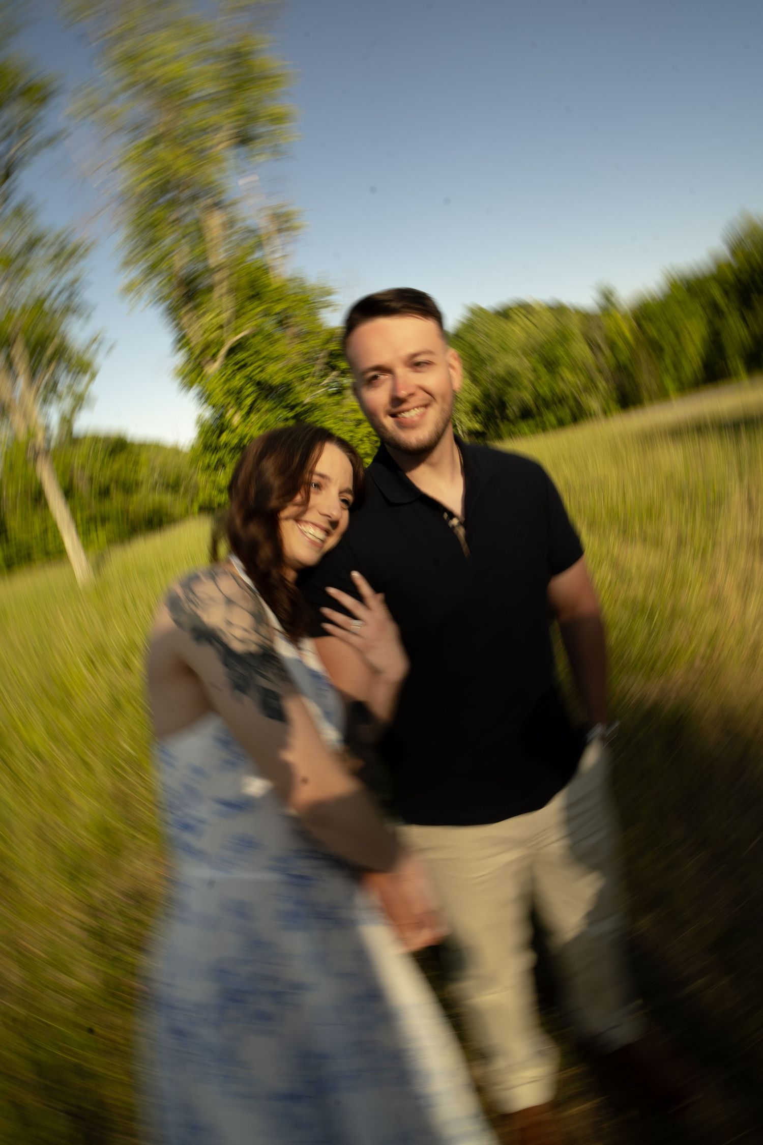Couple smiling together outdoors with a dreamy spin blur effect in a sunny green park.