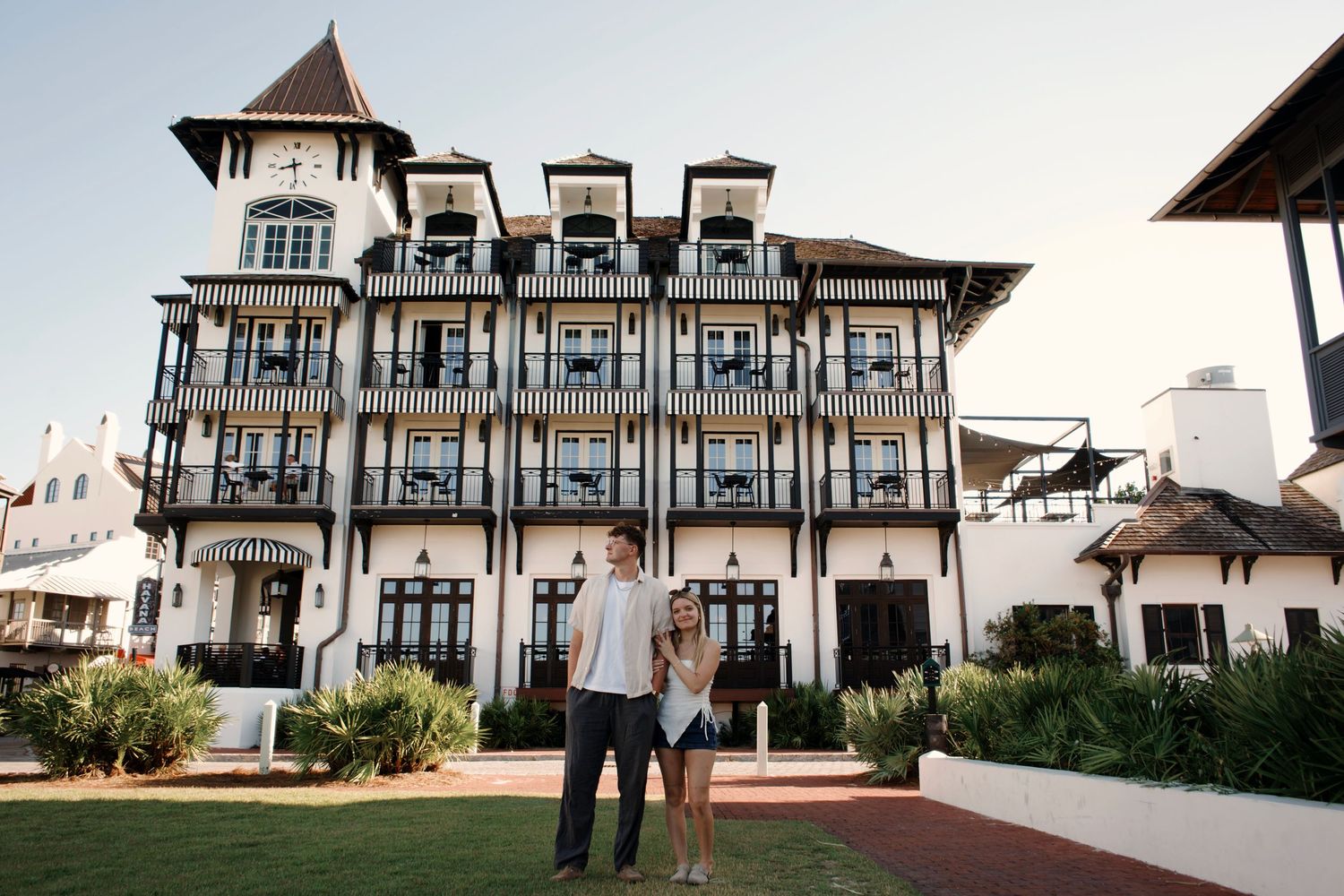 Elegant white Victorian mansion with wrap-around porch and ornate architectural details at sunset.