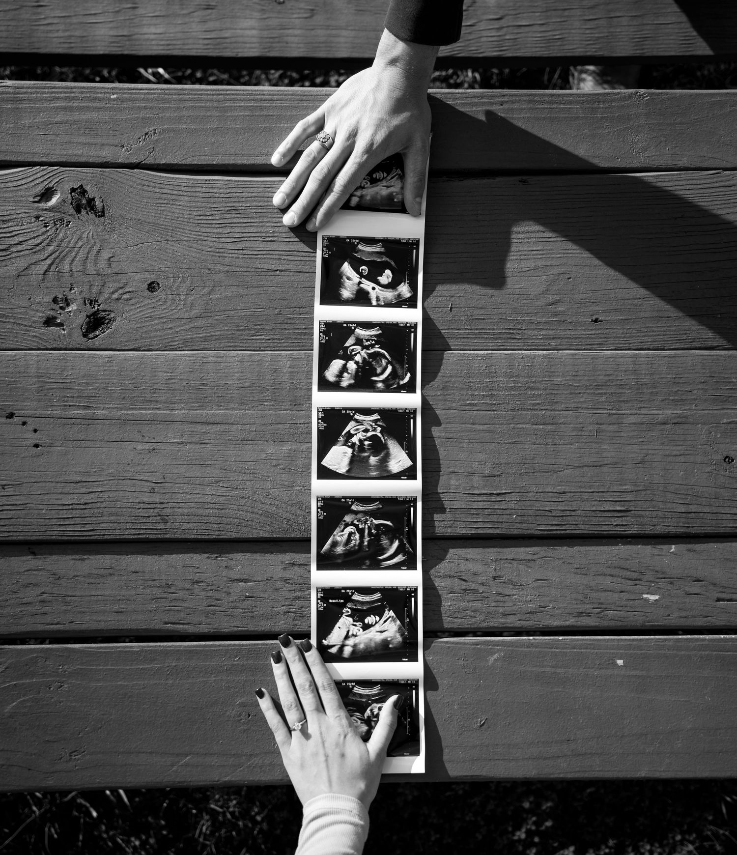 Black and white photo sequence showing hands arranging polaroid photographs on wooden planks in an artistic layout.