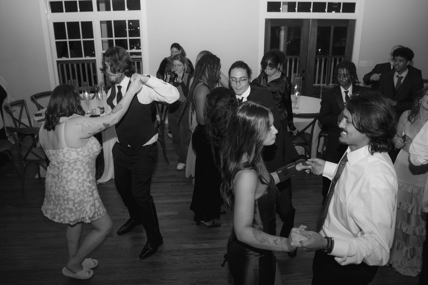 Black and white photo of wedding guests dancing and celebrating at a reception.