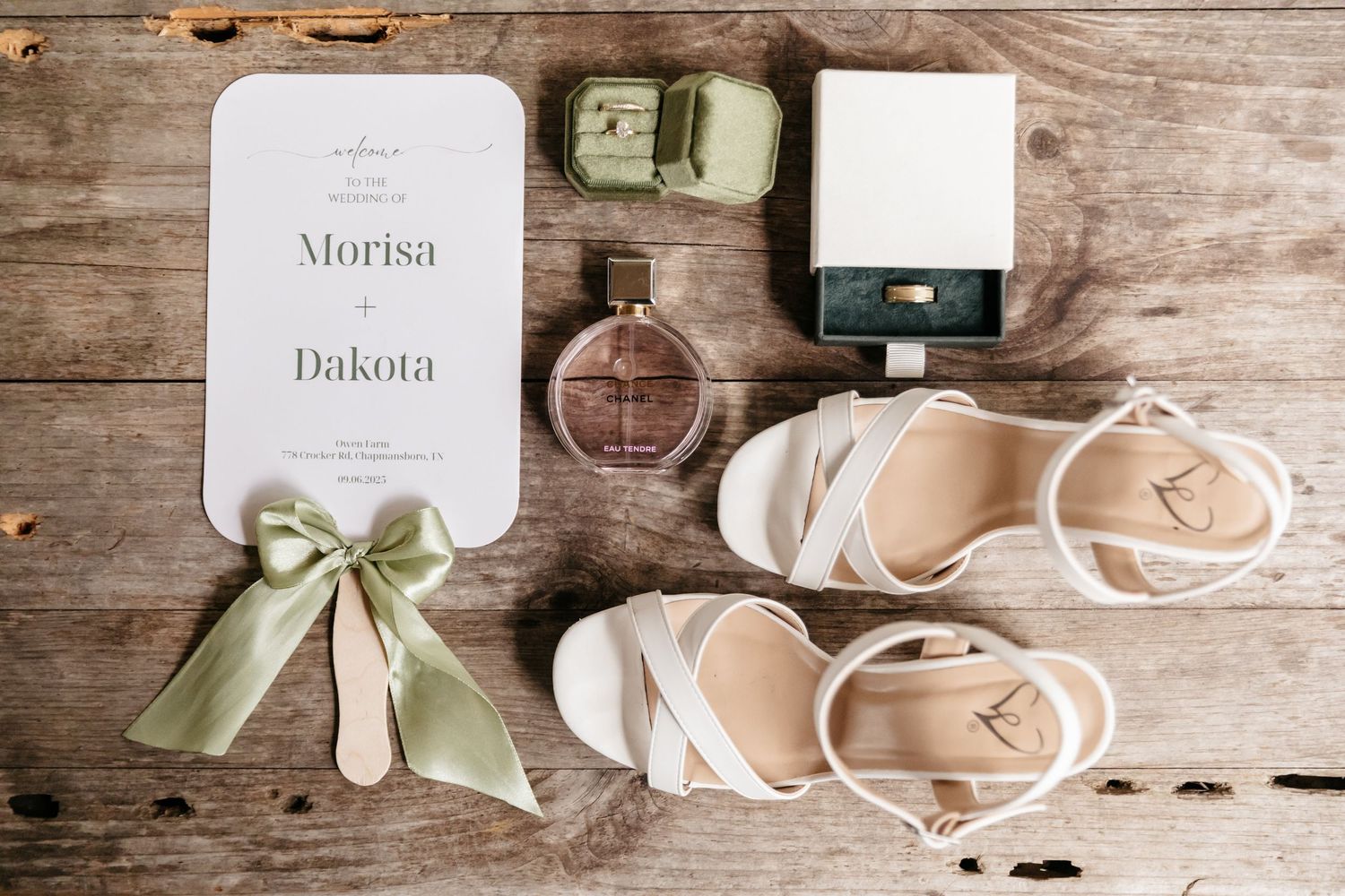 Elegant wedding stationery and accessories arranged on rustic wooden background with silk ribbons and delicate details.