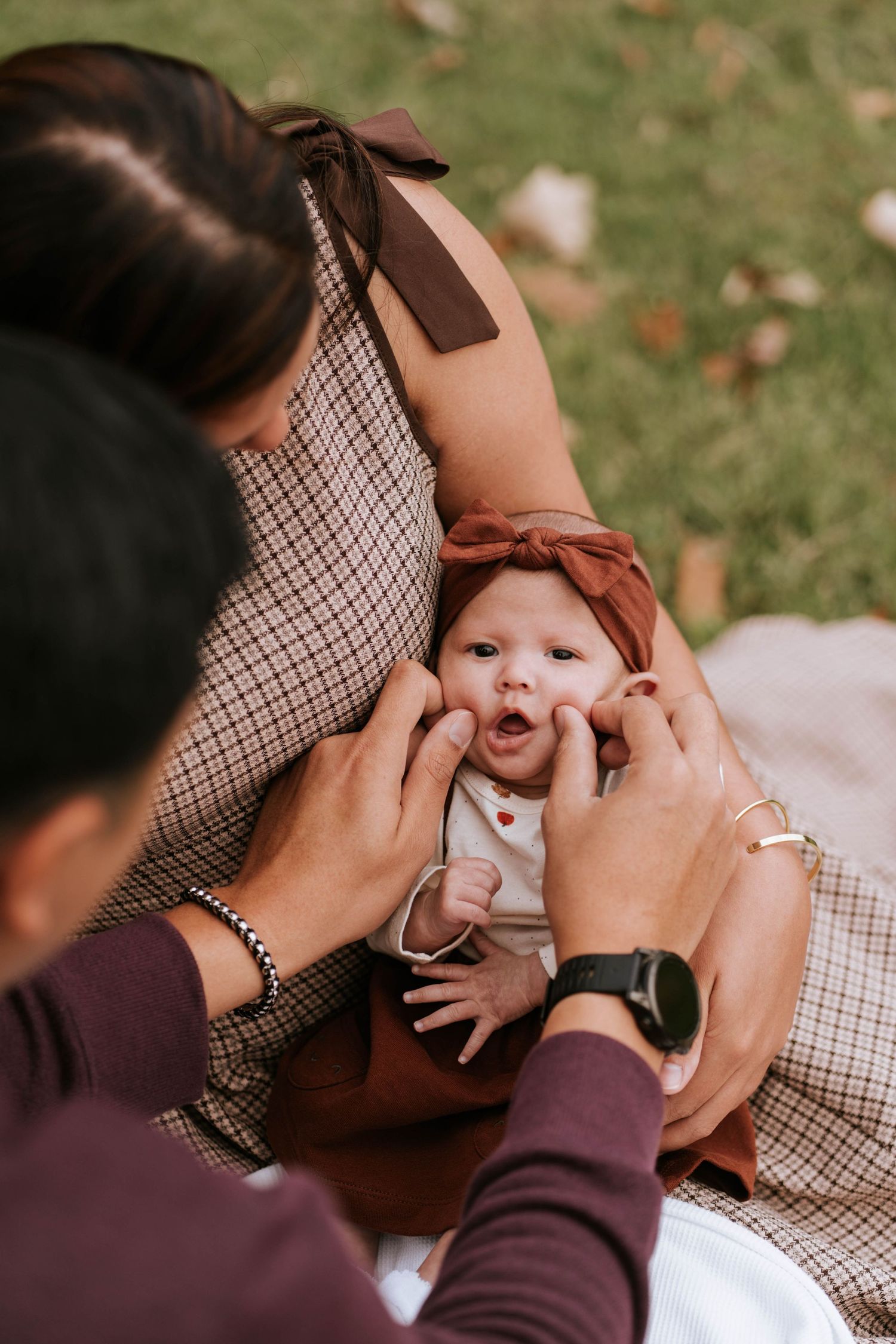 A sequence of photos showing gentle hands tenderly squeezing a baby's cheeks in an outdoor autumn setting.