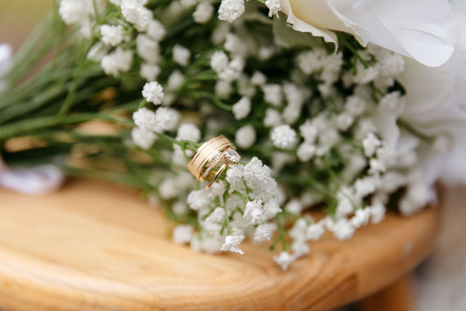 Delicate white baby's breath flowers arranged with green stems on a light wooden surface.