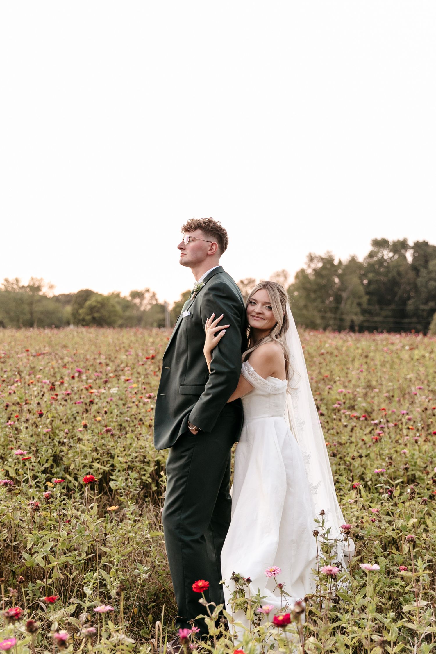 Wedding couple poses in a beautiful field of wildflowers during golden hour.