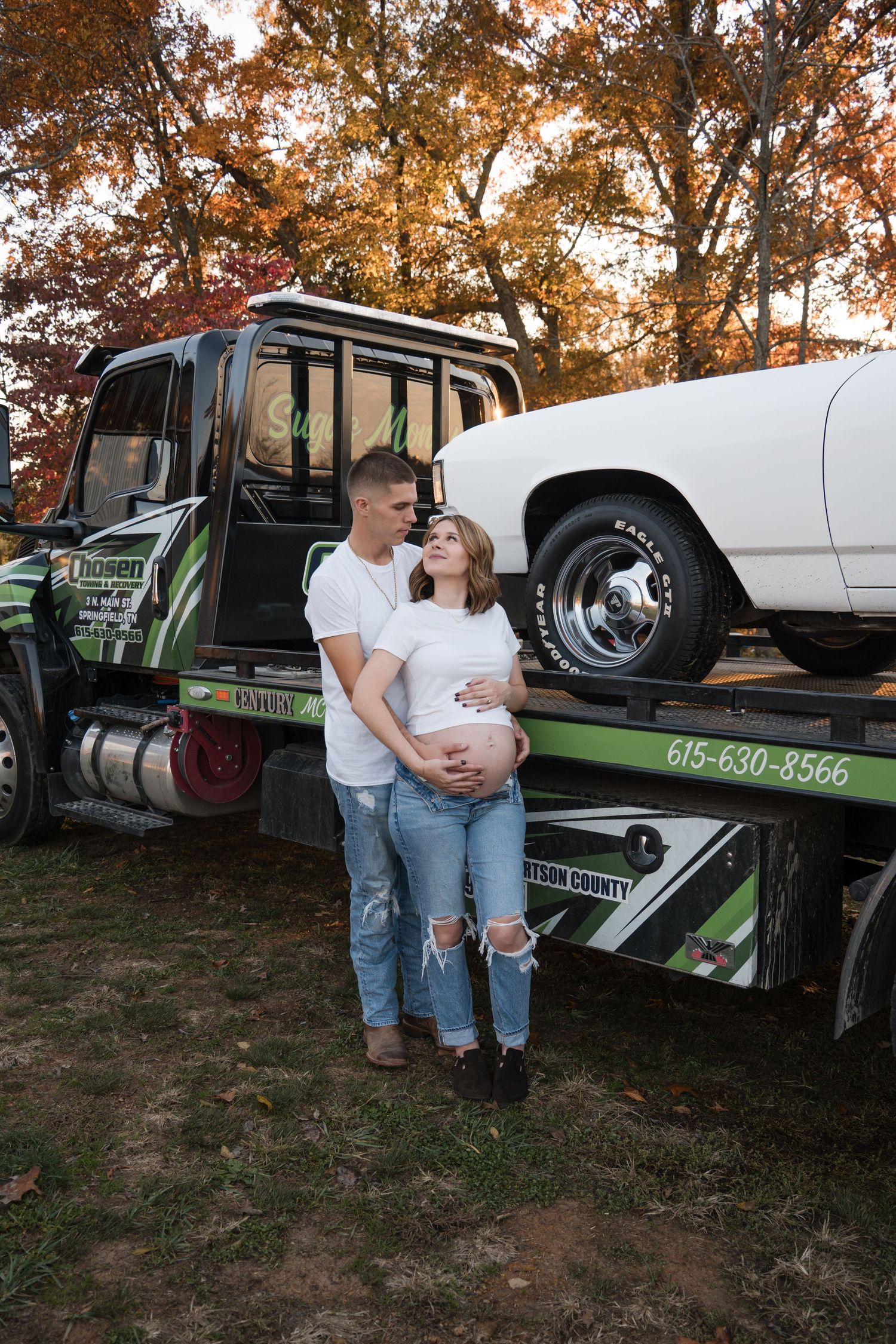 A couple shares a tender moment beside a vintage tow truck during an autumn sunset photoshoot.
