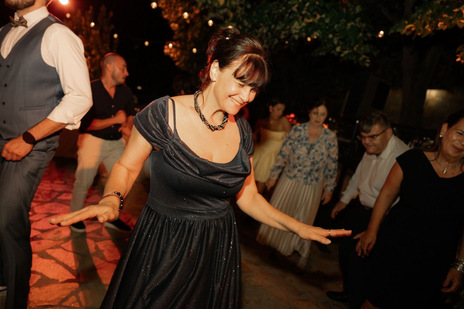 People dance together at a lively nighttime party or celebration with warm lighting and festive atmosphere.