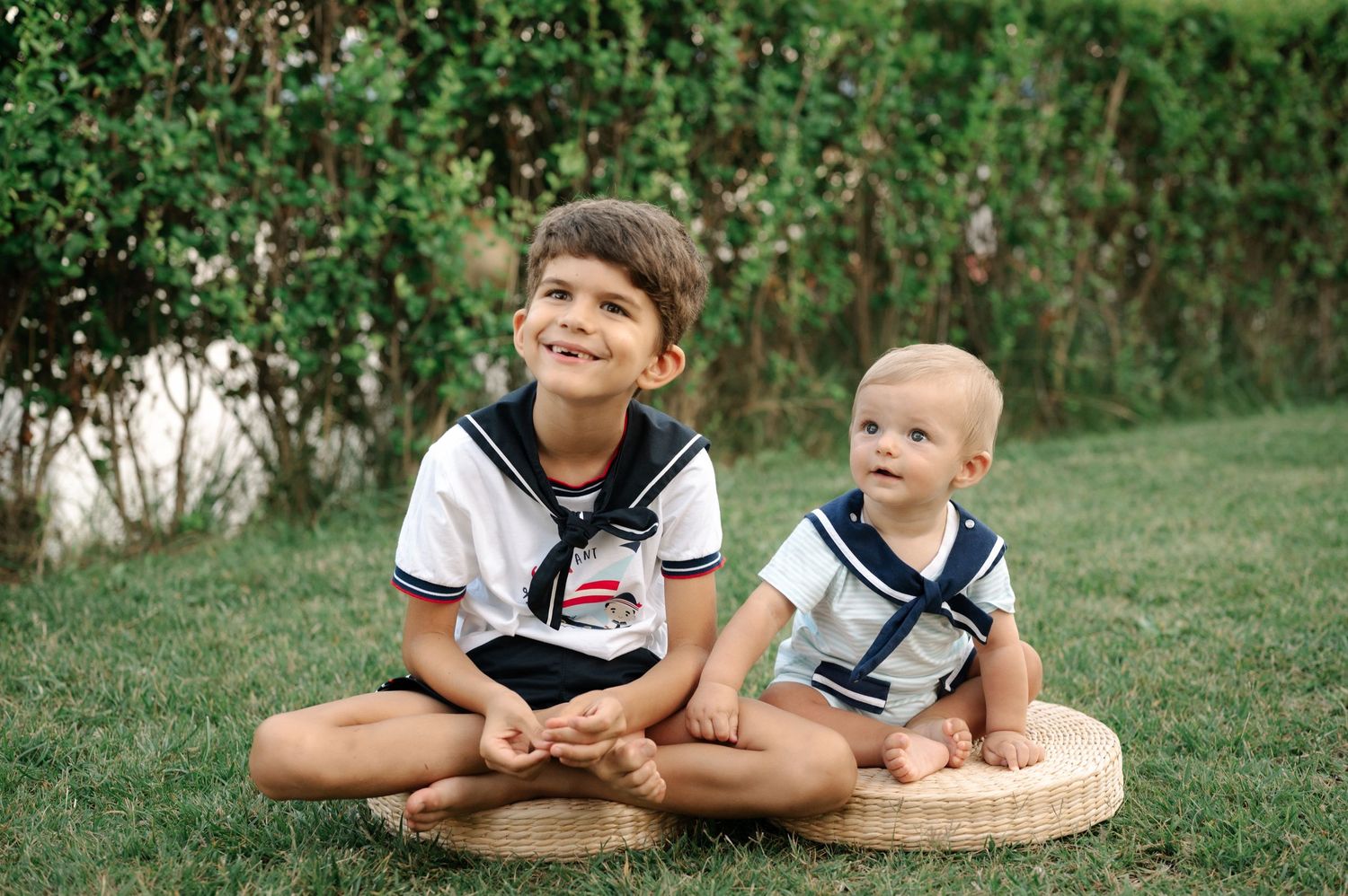 Children laying on grass in matching navy and white outfits during an outdoor photo session.