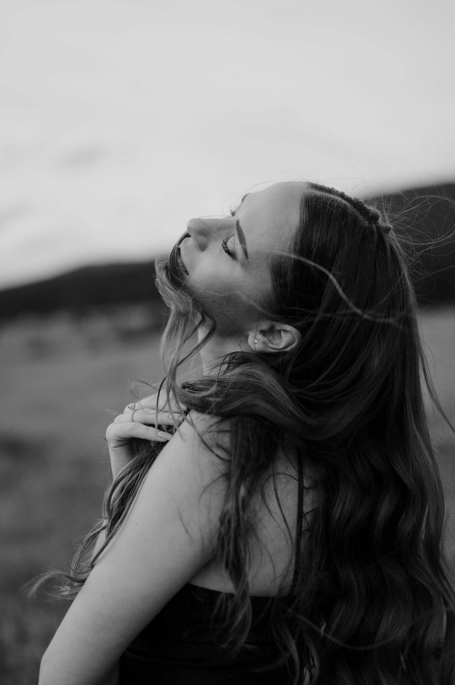 A series of black and white photographs showing windswept hair flowing dramatically against a moody sky.