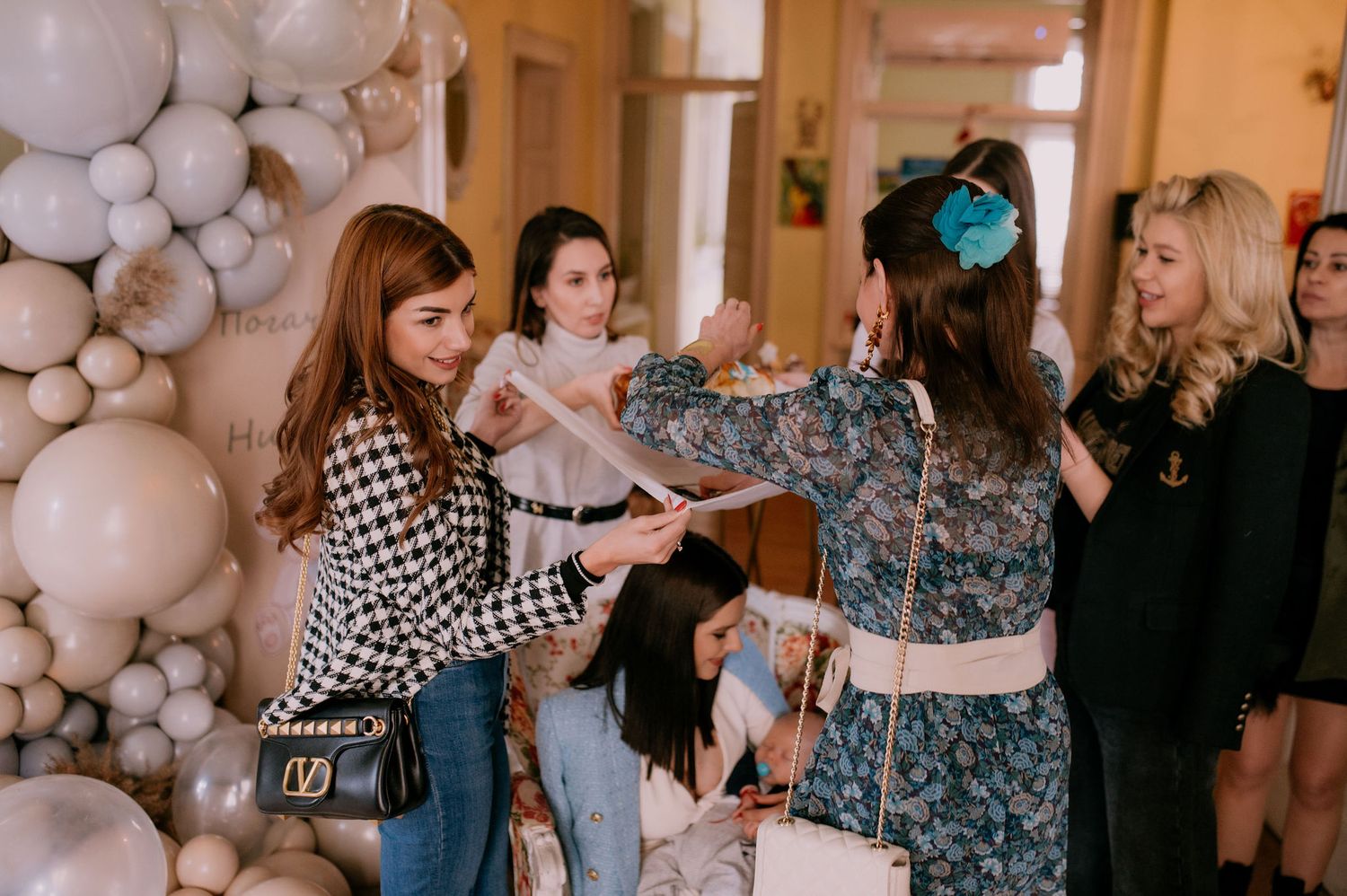 People dancing and socializing at an elegant event with white balloon decorations in the background.