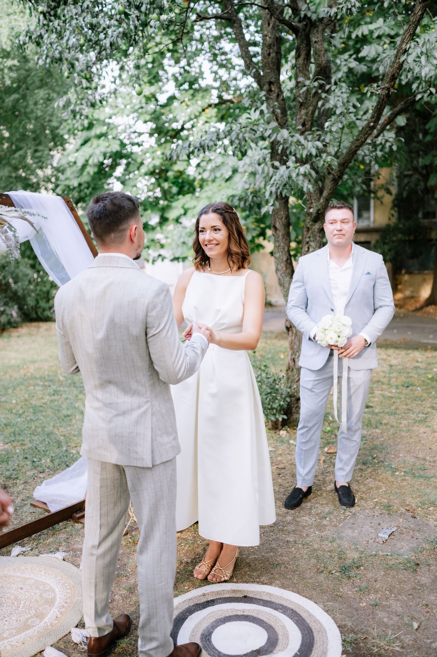 A couple in wedding attire shares a playful dance moment in a wooded outdoor setting.