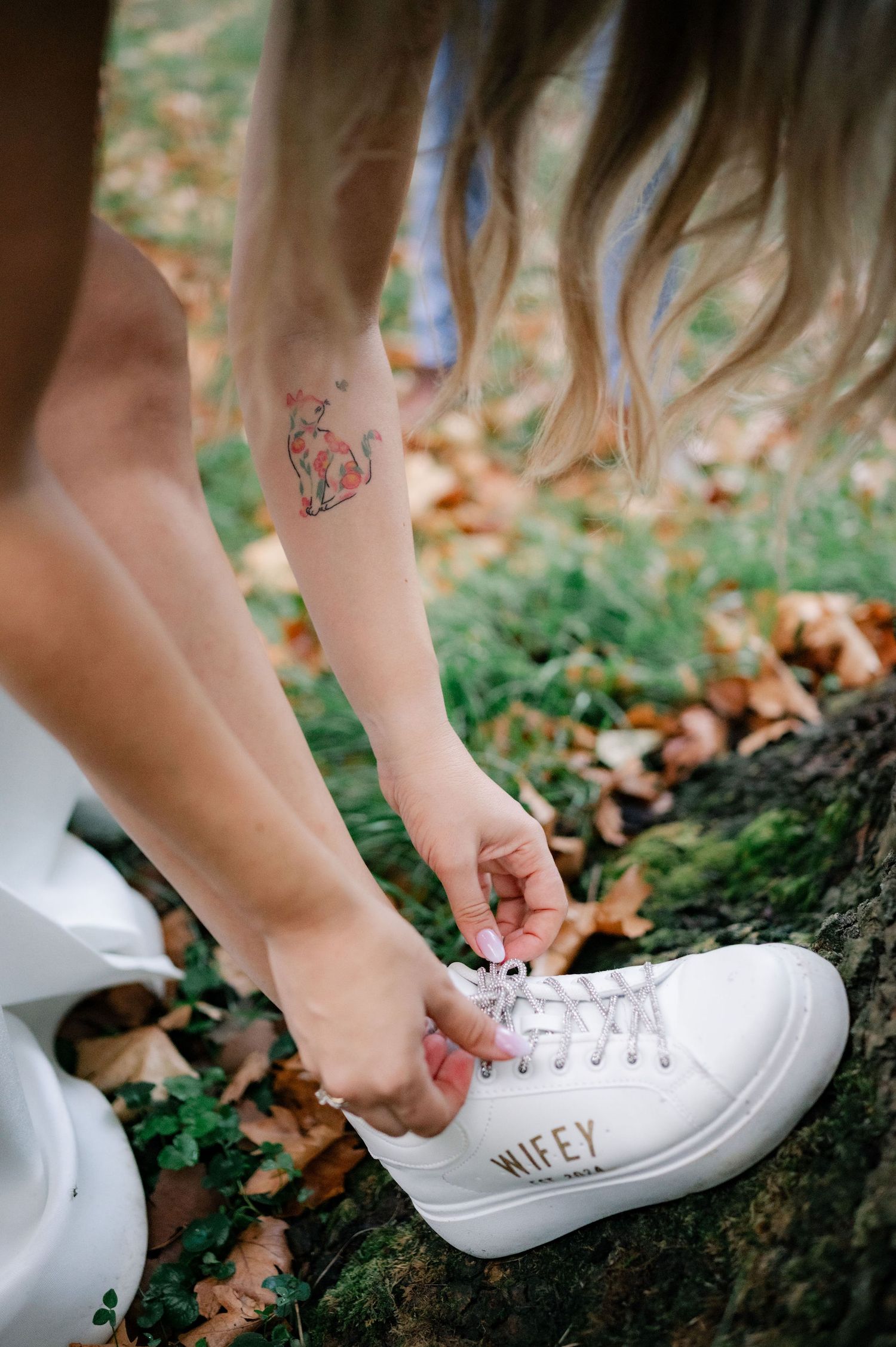 Close-up sequence showing someone tying white sneakers with colorful tattoos visible on their ankle and foot.