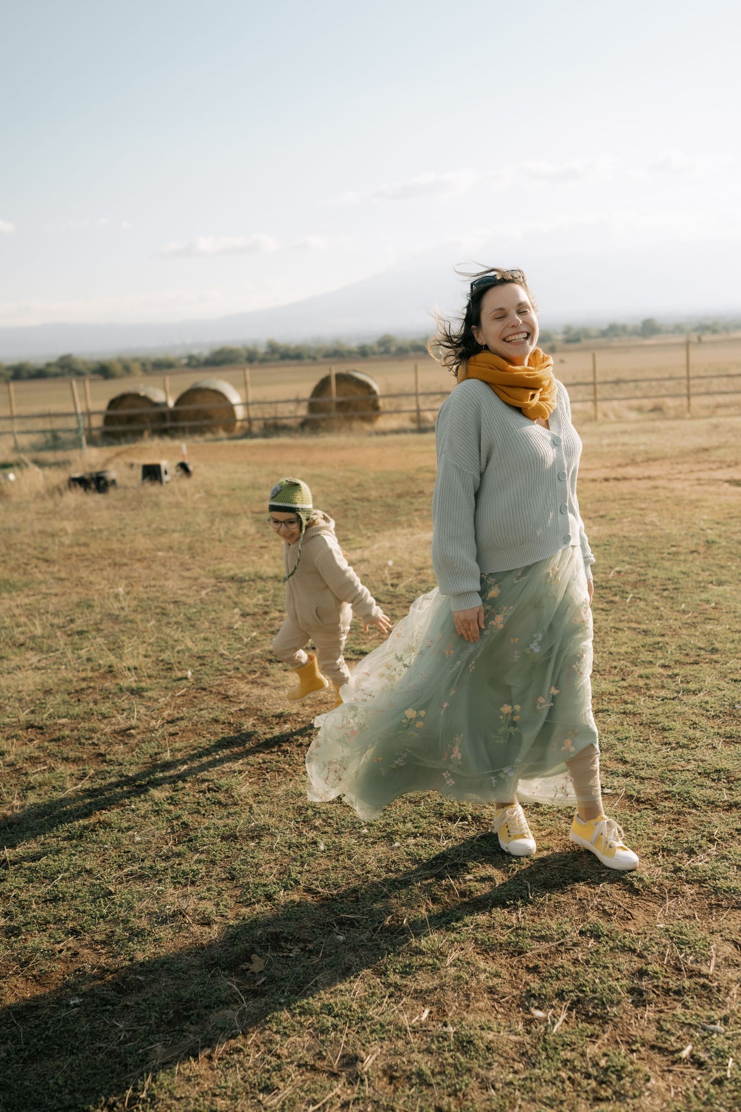 People enjoying a sunny day in a rural field with mountains visible in the background.
