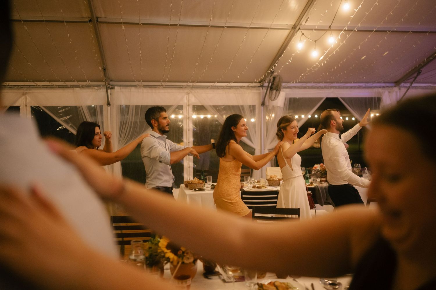 People enjoying themselves on a dance floor under warm lighting at a wedding reception venue.