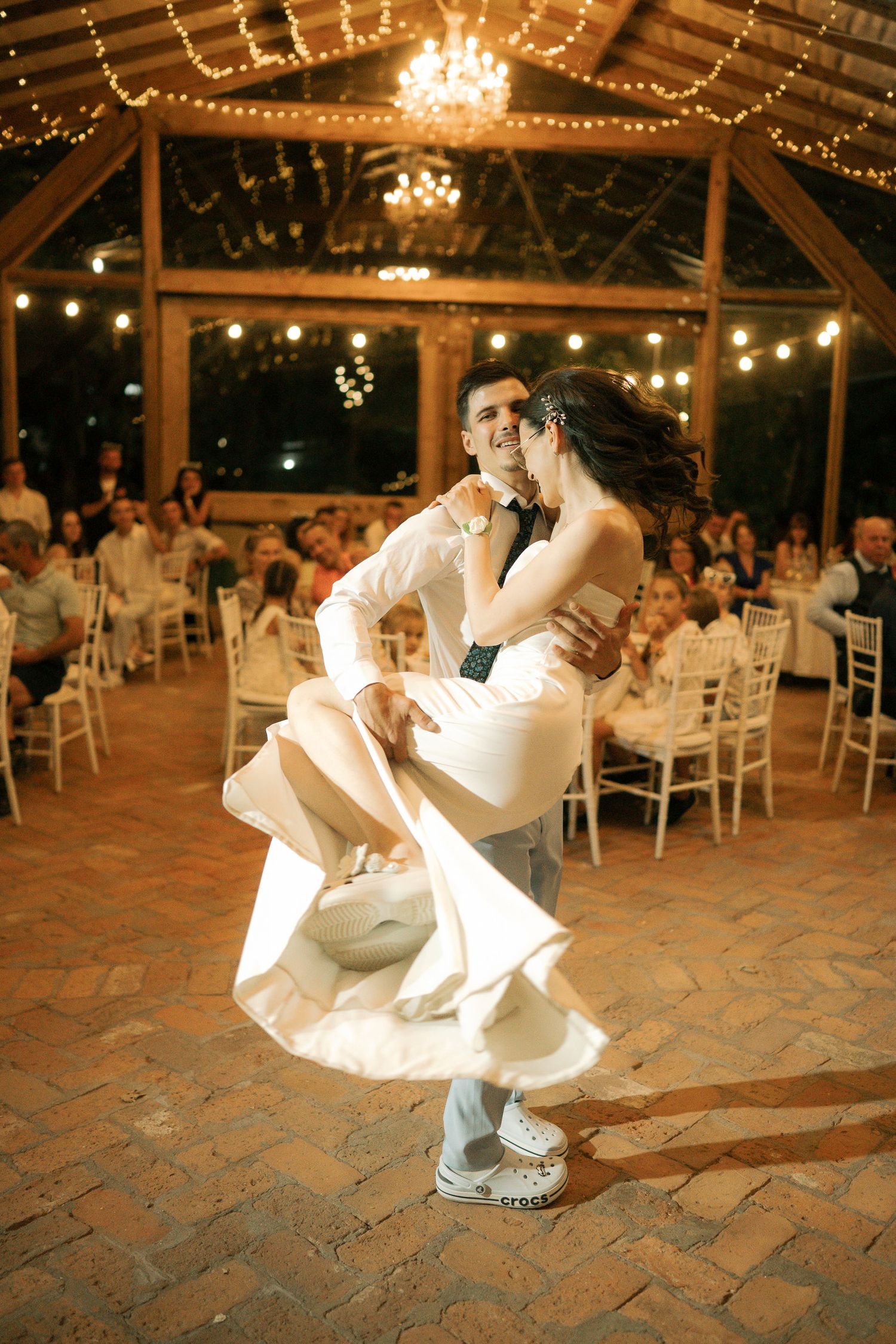 A sequence of dance moves captured at a wedding reception under twinkling lights and chandeliers on a stone floor.
