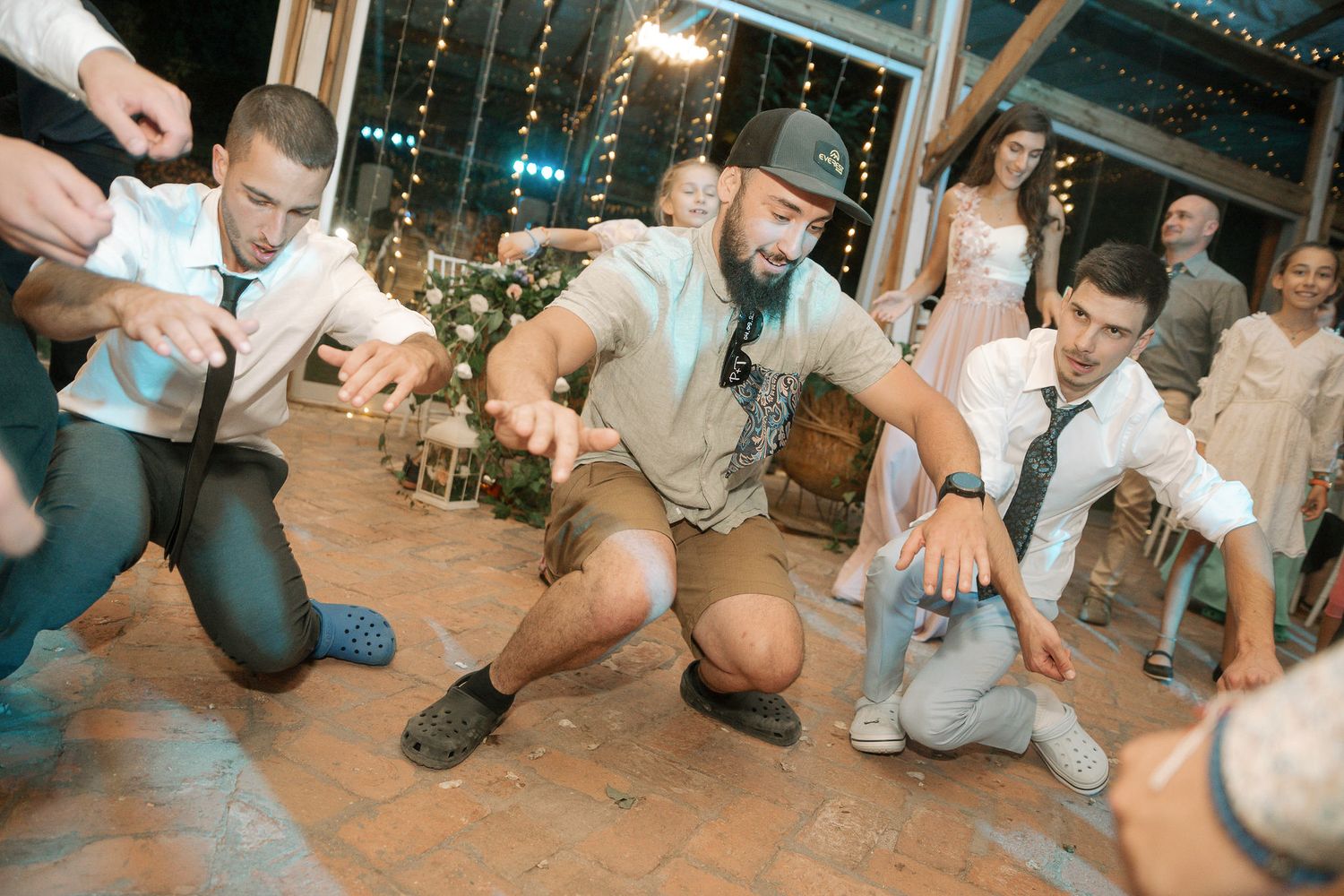People sitting on ground in a row performing a coordinated dance or game routine in an indoor venue.