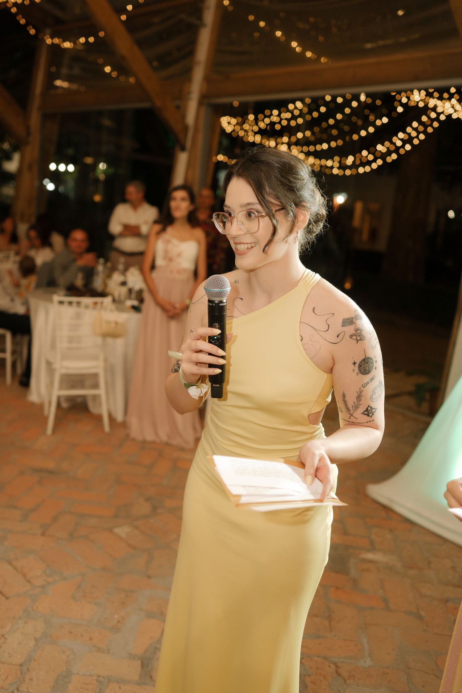 Wedding guests dancing together under twinkling string lights at an evening reception on a stone patio.