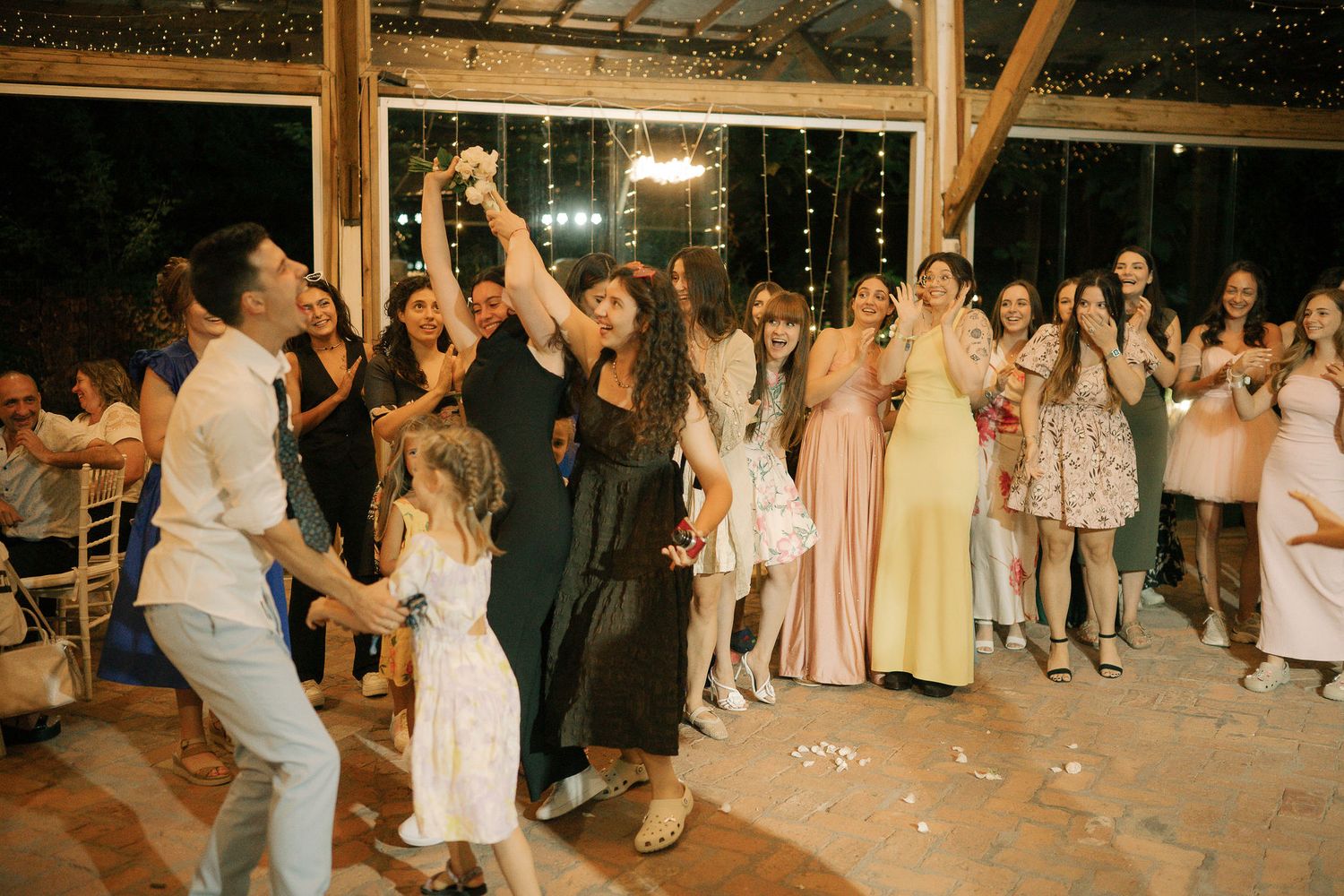 Wedding guests dance together on an outdoor dance floor during an evening reception celebration.
