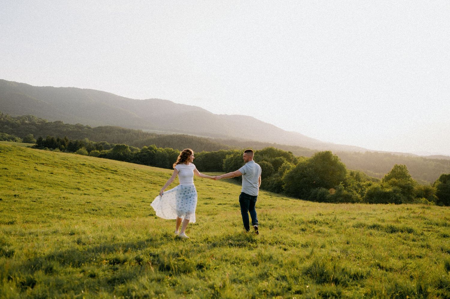 Couple enjoys a romantic moment on a hilltop meadow during golden hour.