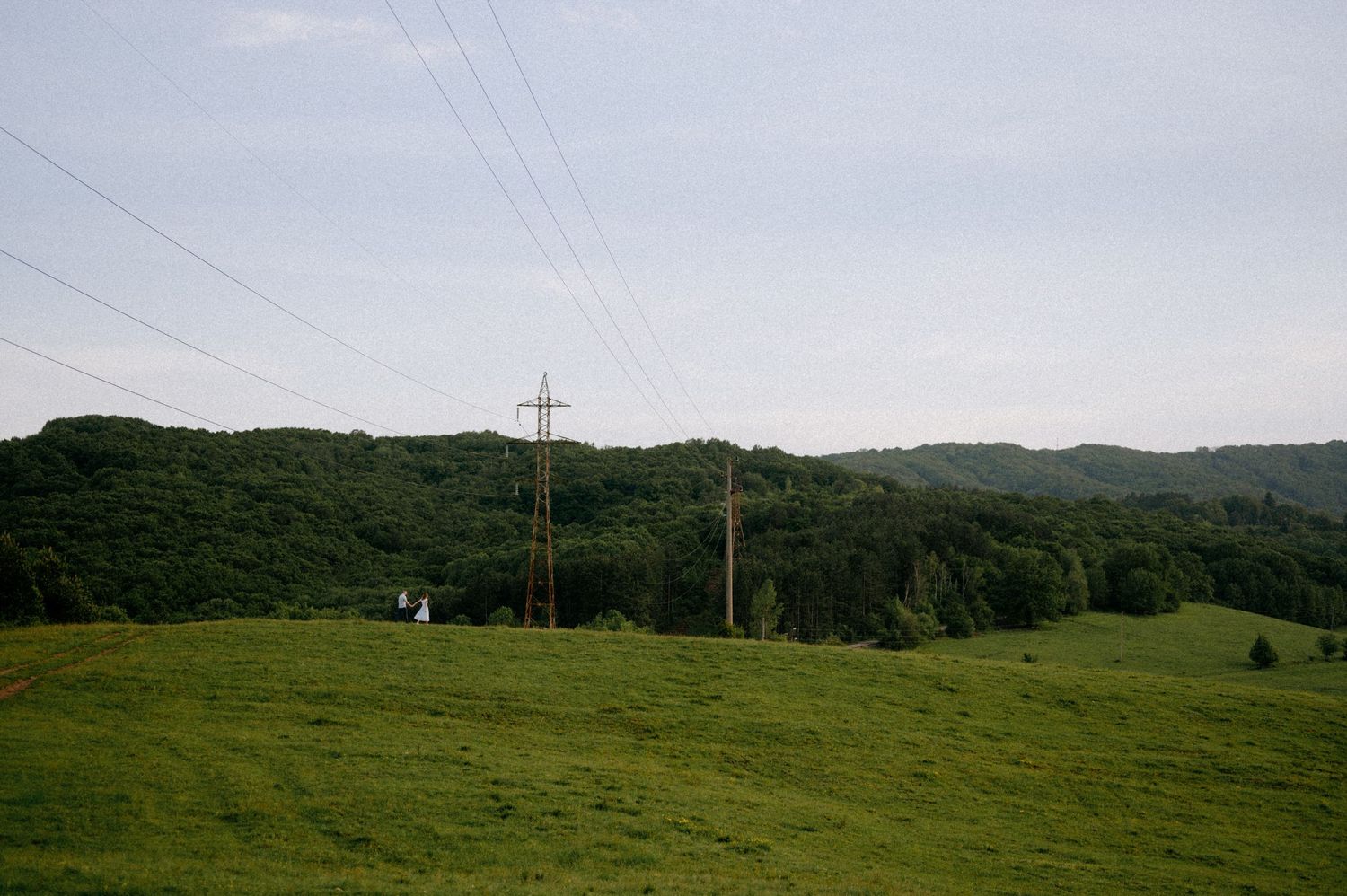 High-voltage transmission towers dotting the horizon of a peaceful rural meadow.