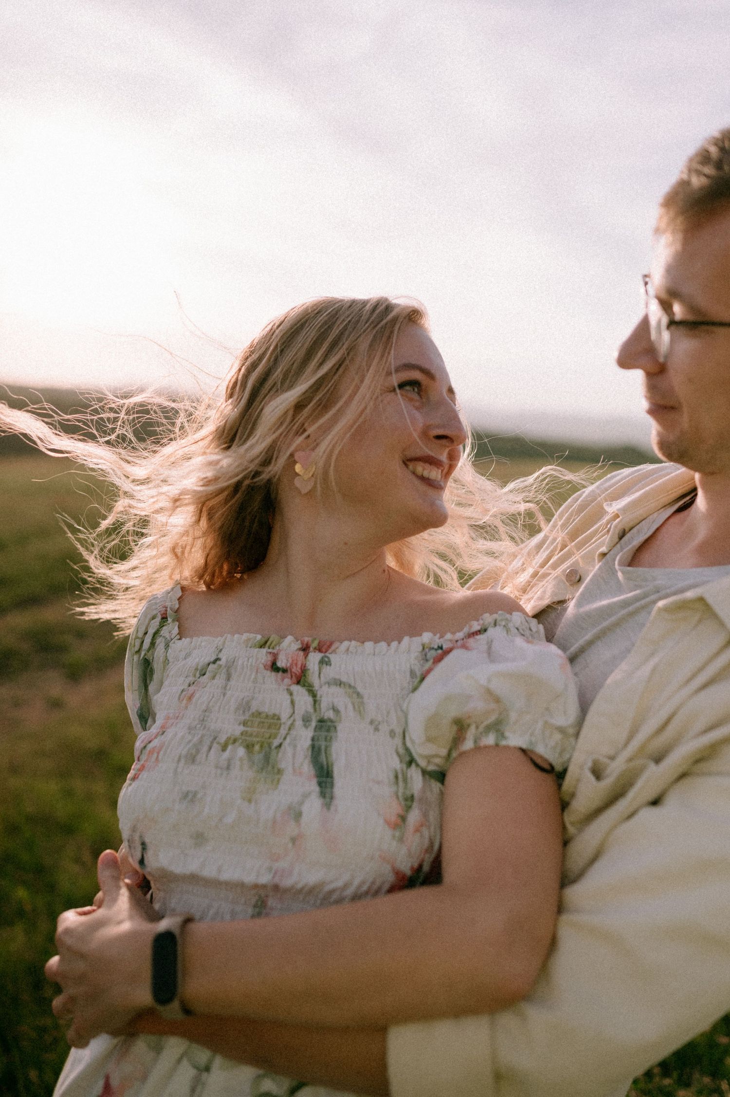 Couple sharing intimate moment in golden light with wind blowing through hair.