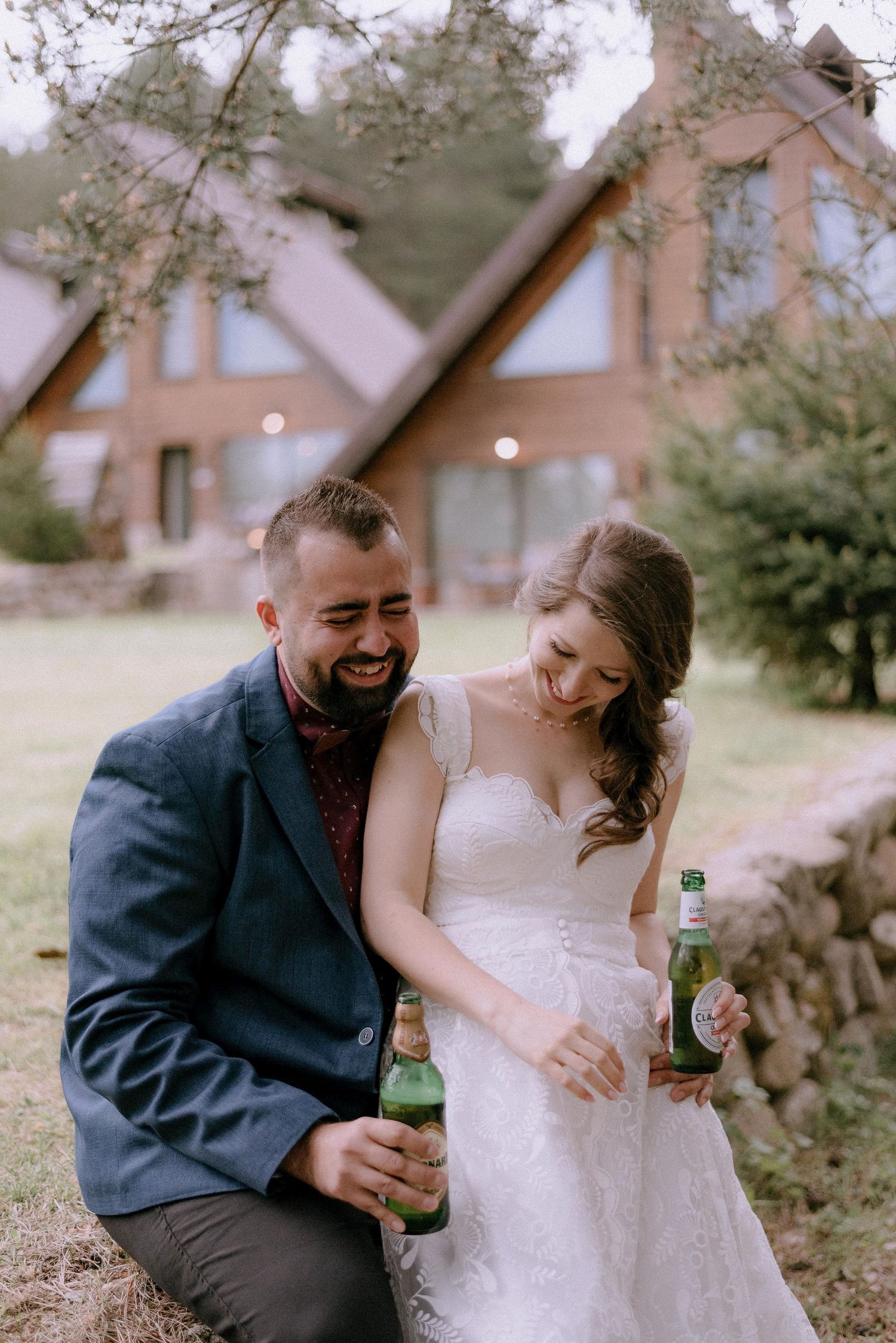 A couple laughs together while sharing drinks on a rustic outdoor property.