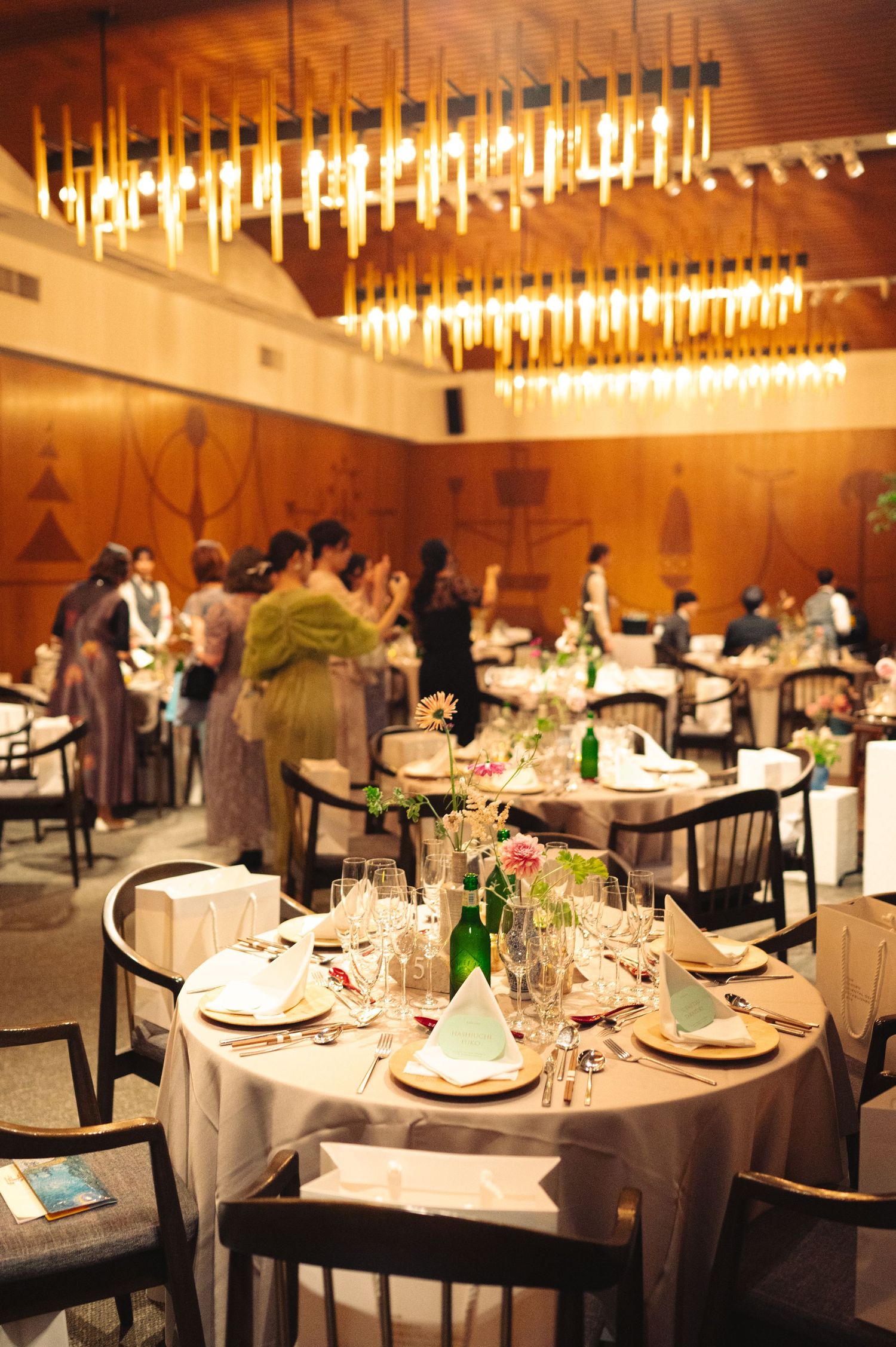 Wide view of formal dining room with round tables set for an upscale event under crystal chandeliers.