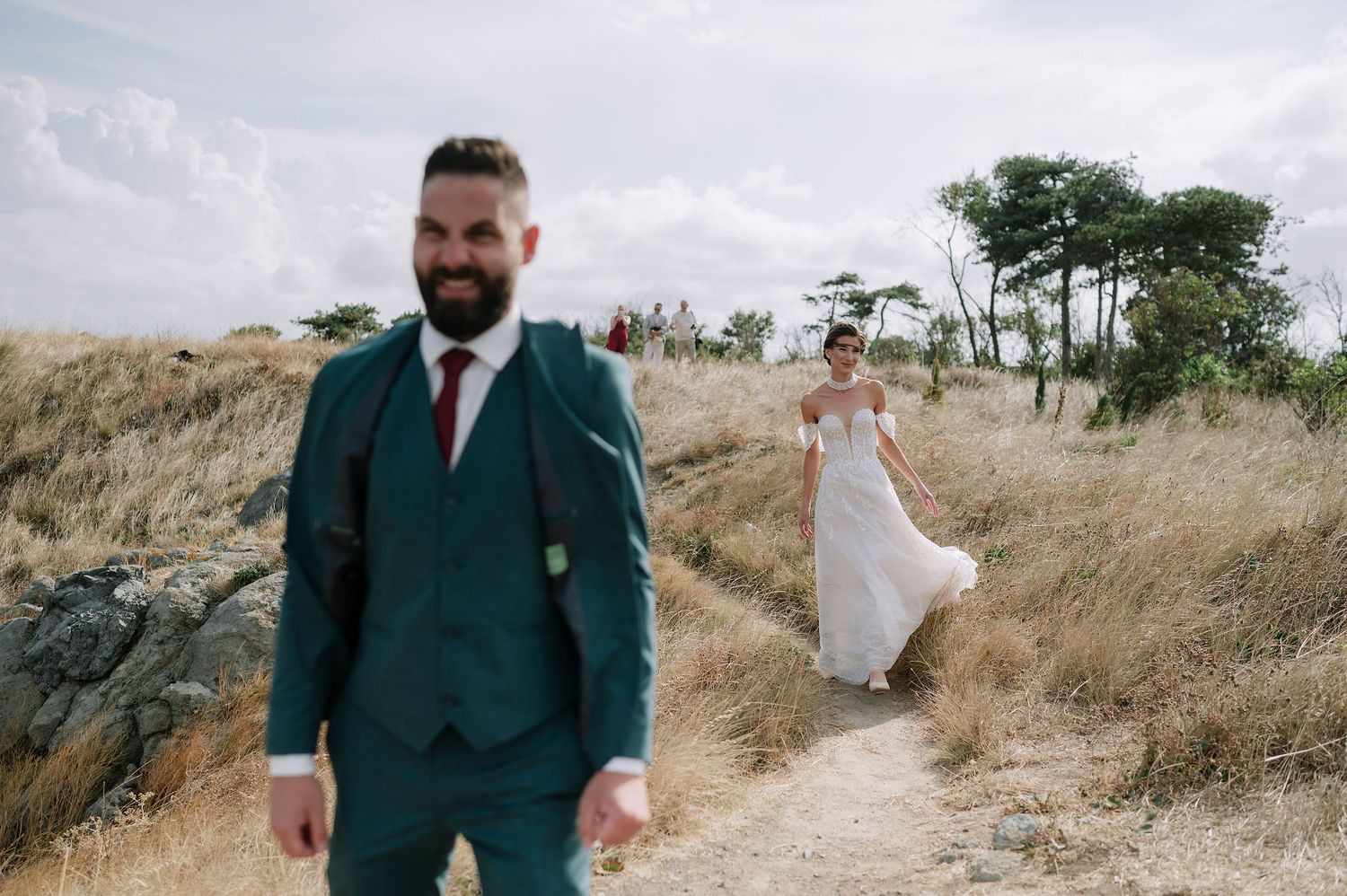 Wedding couple sharing a moment together on a grassy coastal path.