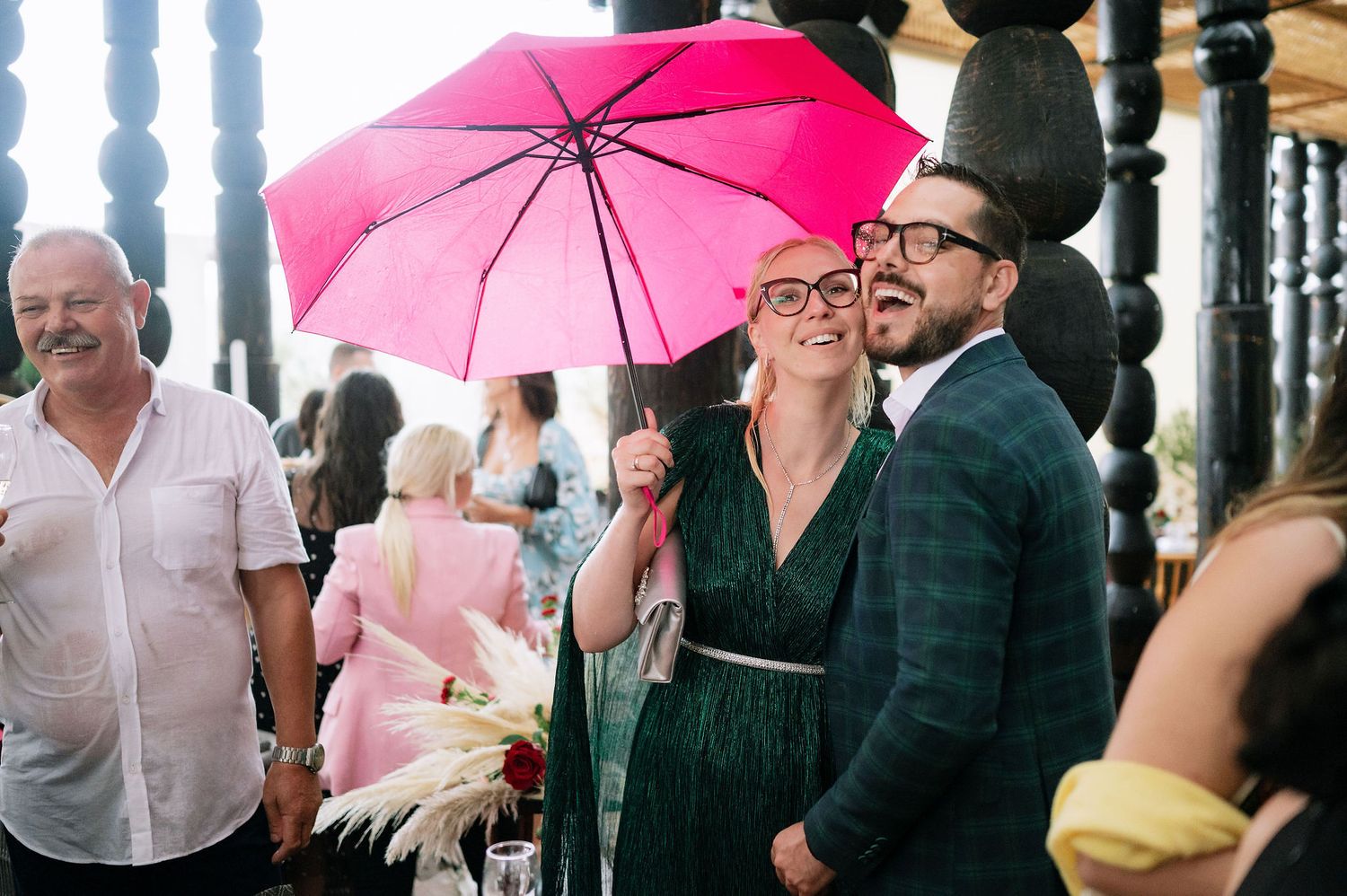 People holding pink umbrellas at an outdoor gathering.