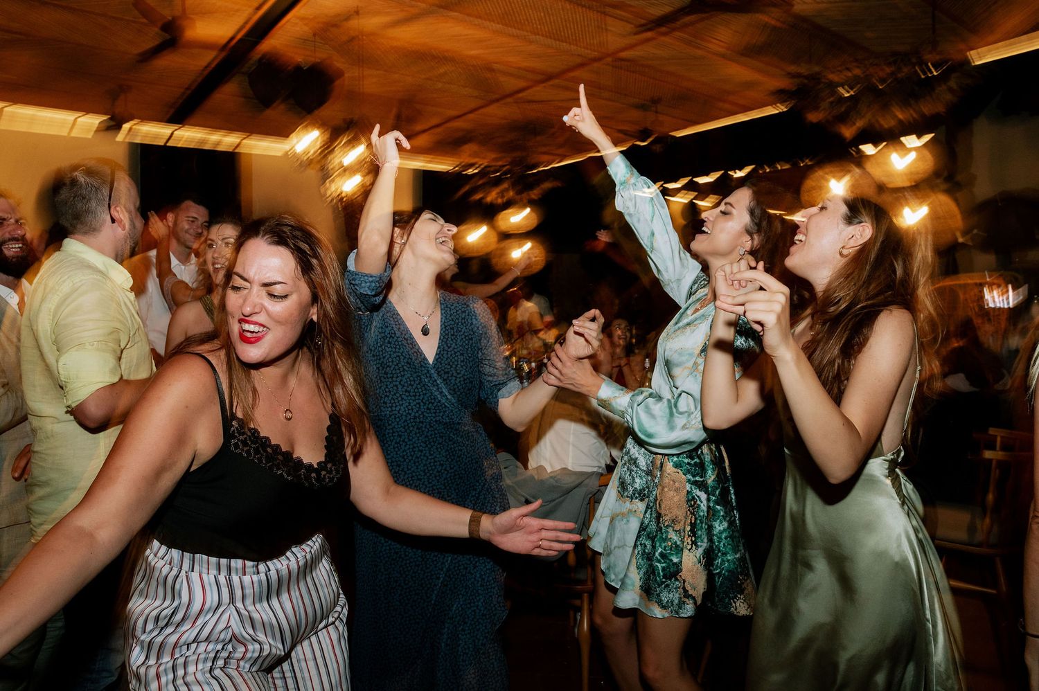 Lively party scene with guests dancing and celebrating under warm ambient lighting.