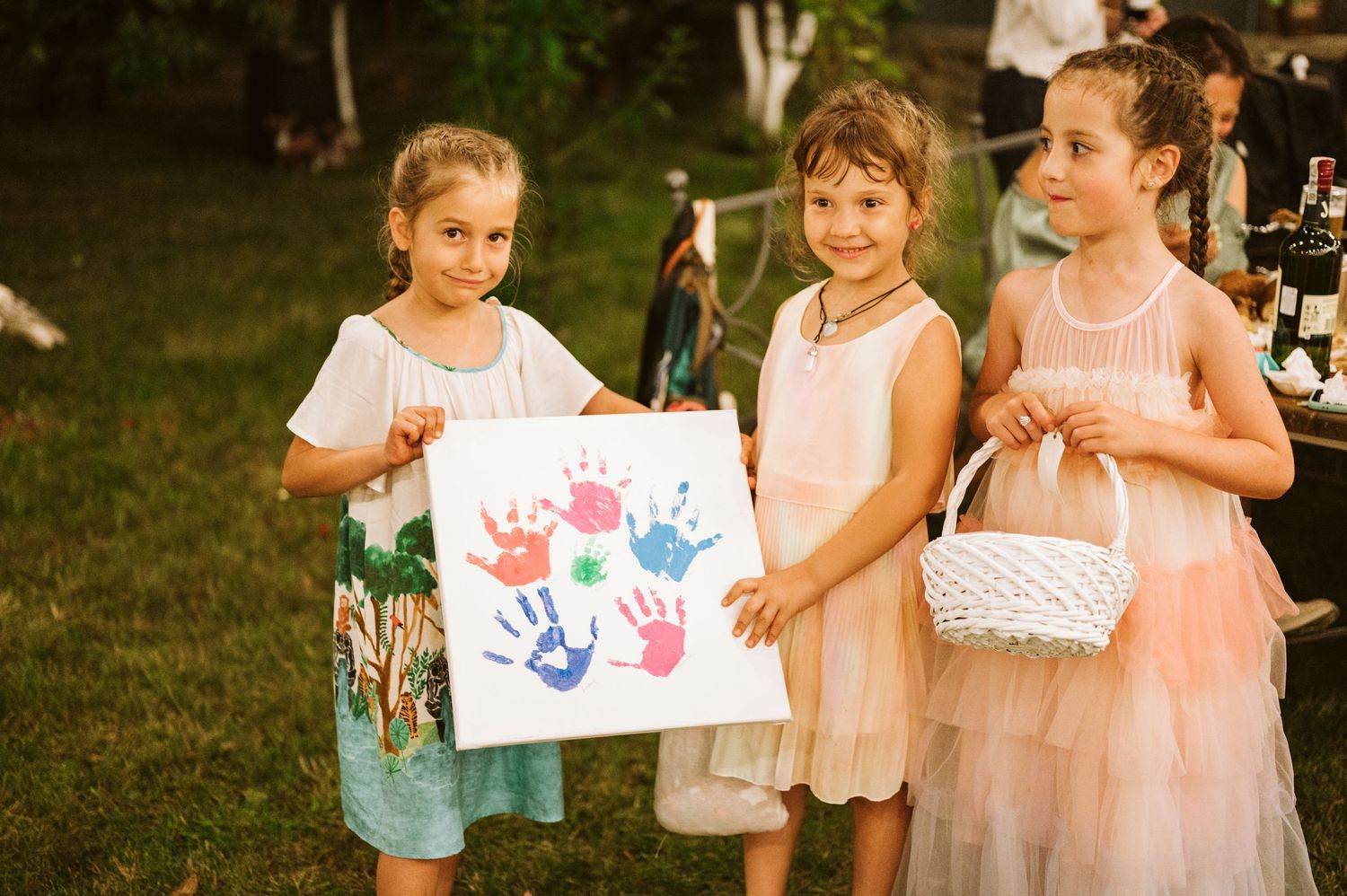 Children showing off their colorful handprint artwork outdoors.